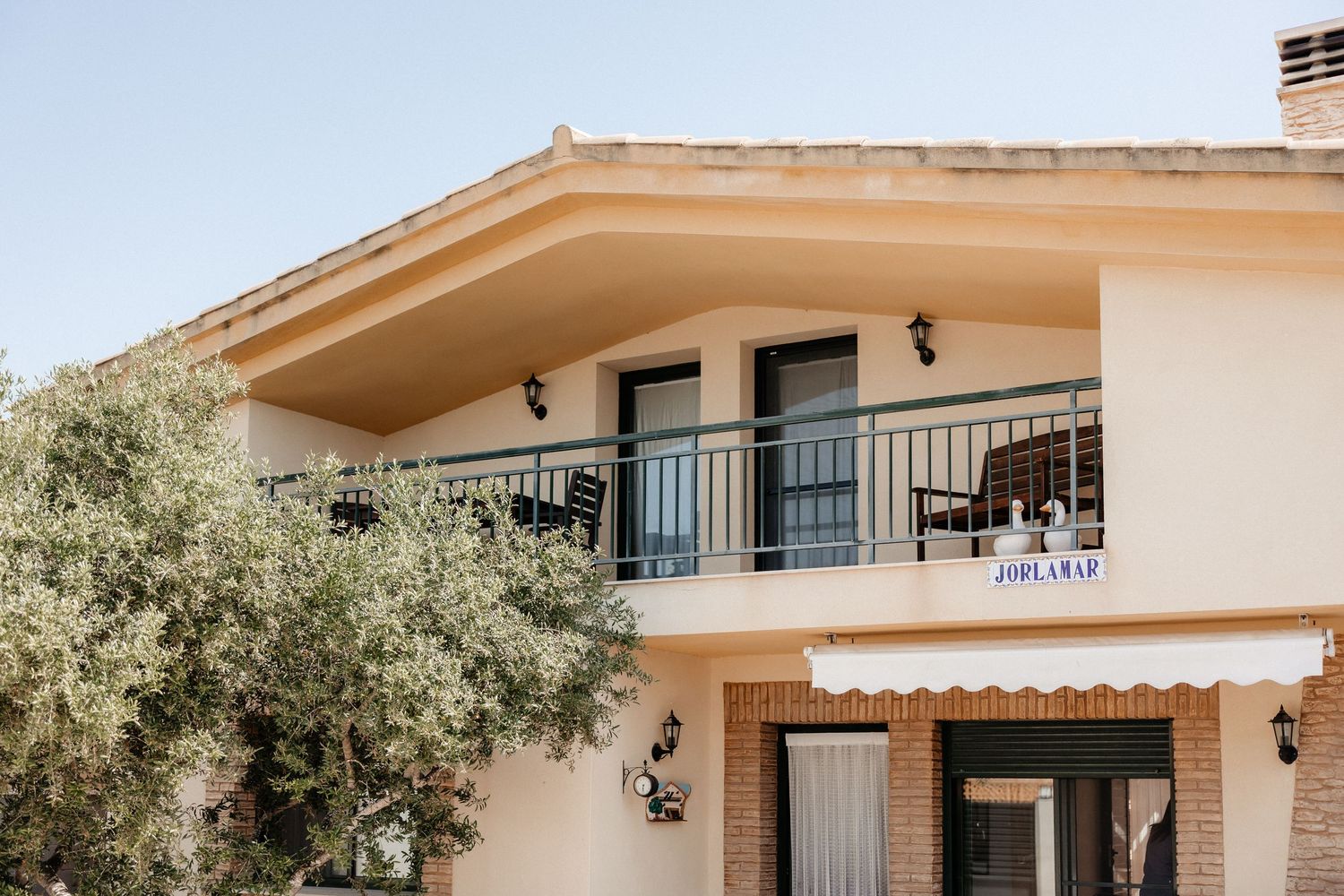 A modern beige stucco house with black iron balcony railings and an American flag mounted on the exterior. Wedding in Les Moles.