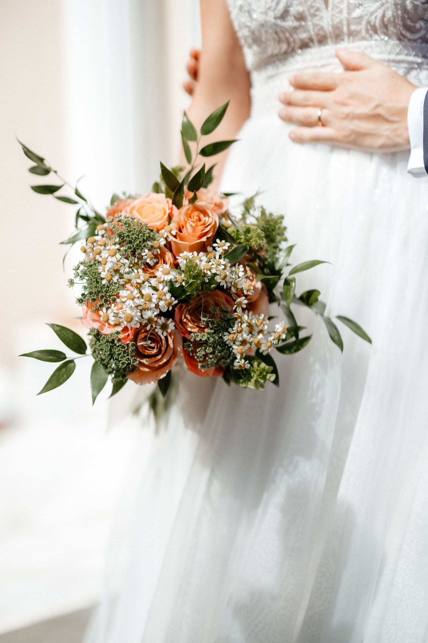 A delicate bridal bouquet featuring peach roses, white flowers and eucalyptus greenery against a light background. Wedding in Villa Retiro.