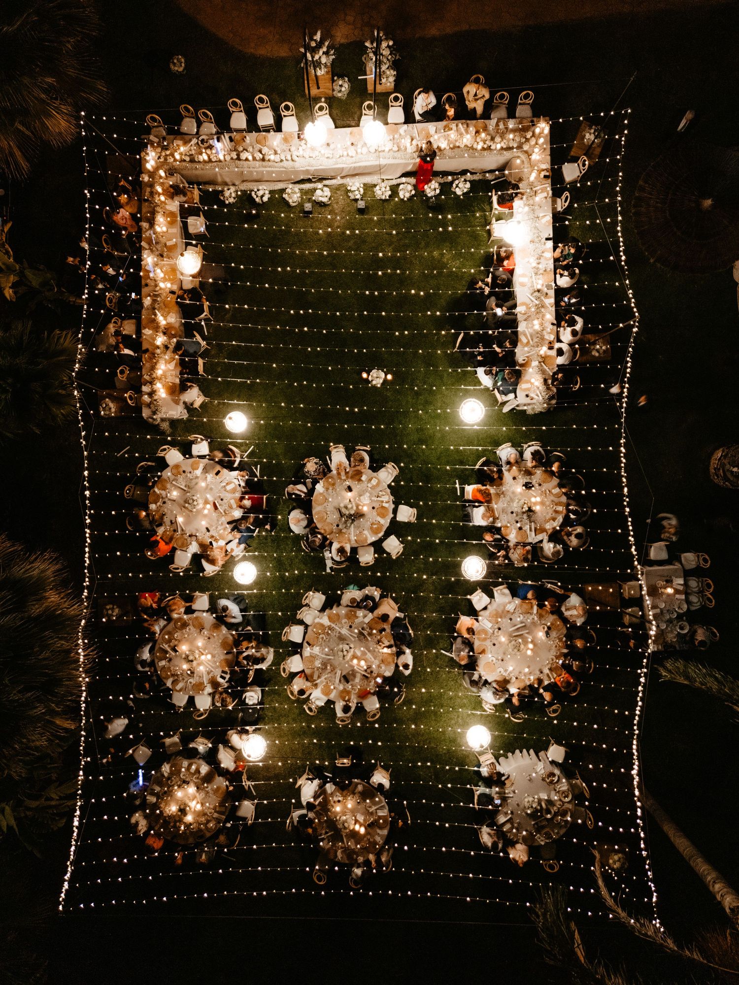 Wedding reception at night with illuminated circular tables and decorative string lights creating a magical atmosphere. Villa retiro.