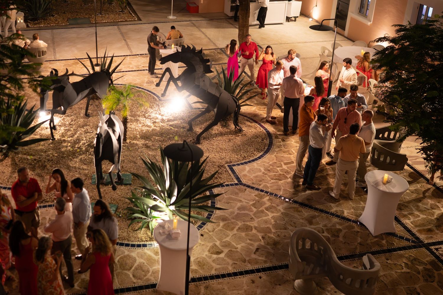 Nighttime outdoor event with string lights illuminating a courtyard filled with guests.