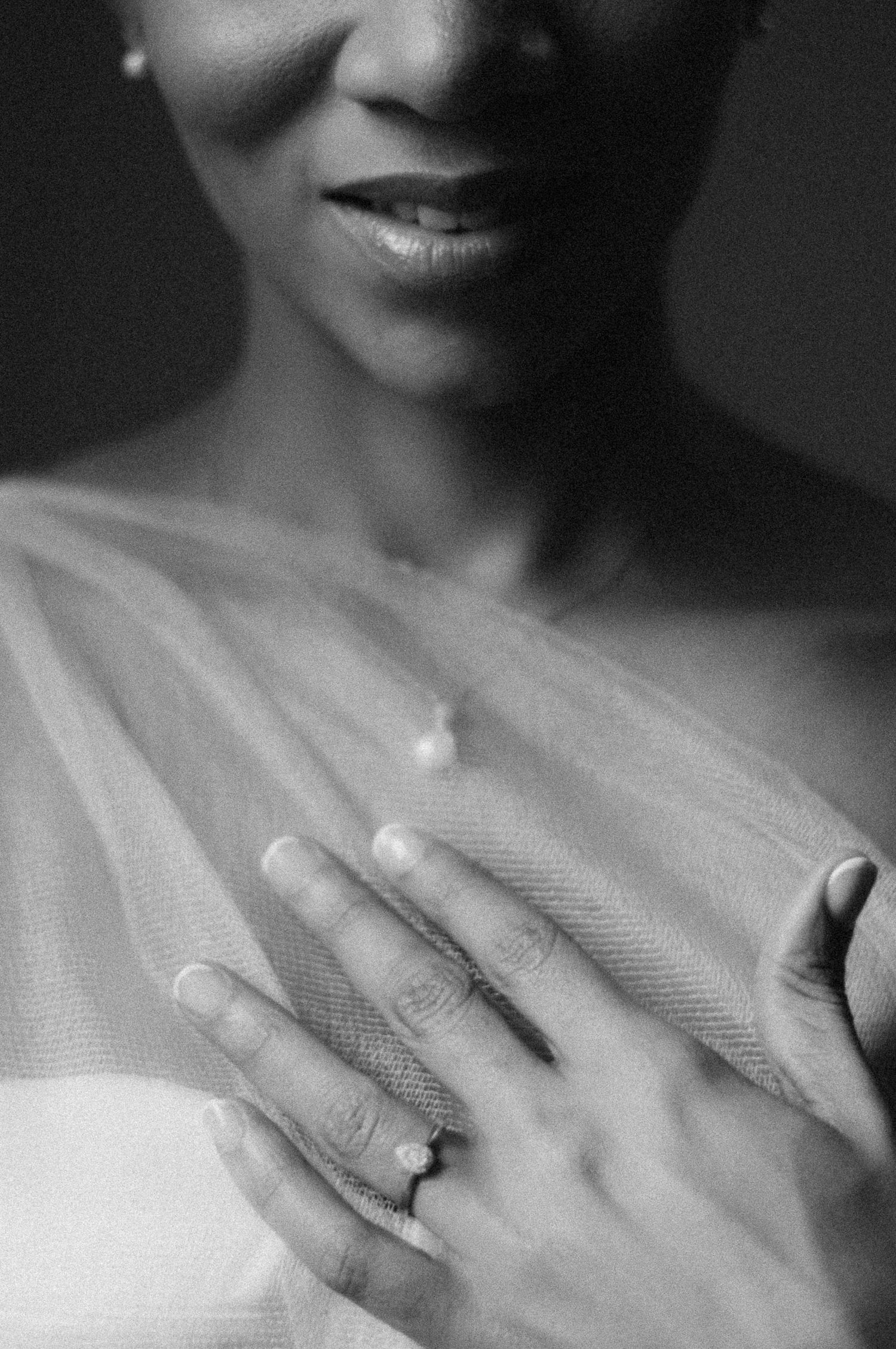 Close-up black and white photo of a wedding ring and delicate white fabric.