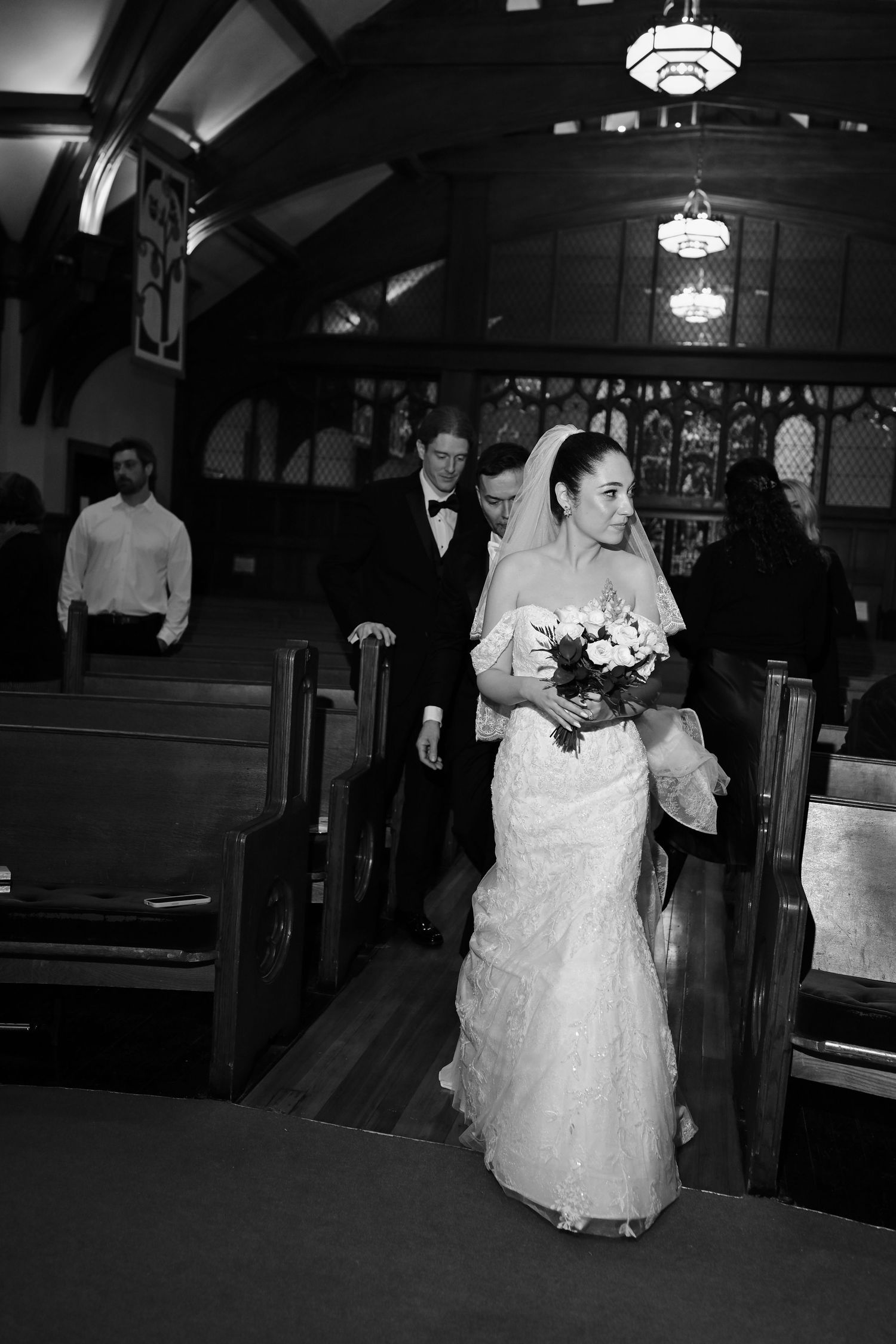A bride walks down the church aisle in an elegant mermaid-style wedding dress.