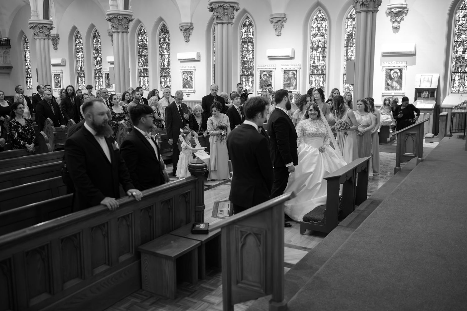 Wedding ceremony in a traditional church with gothic arches and stained glass windows.