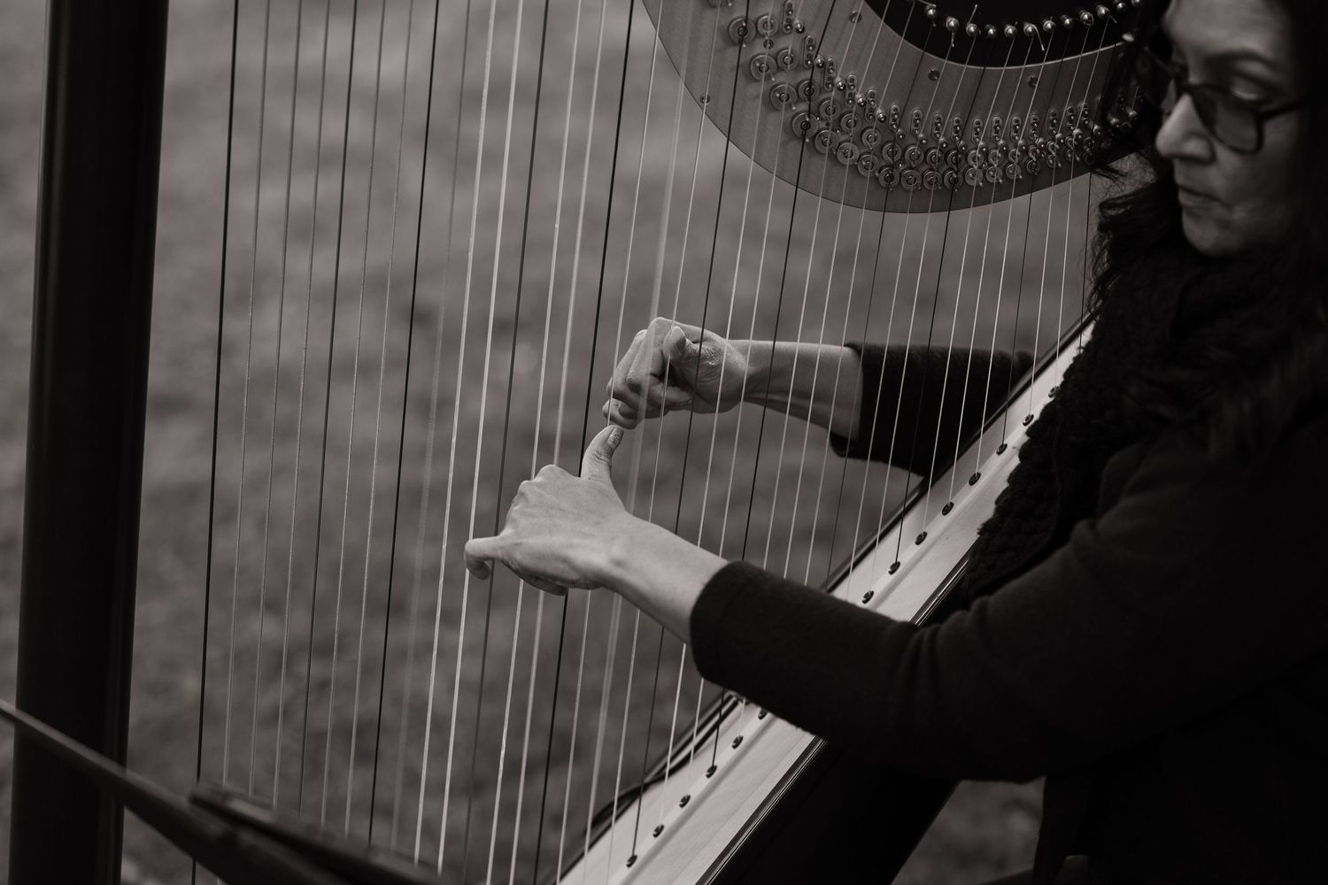 A woman playing a harp at a wedding reception in a black and white photo.
