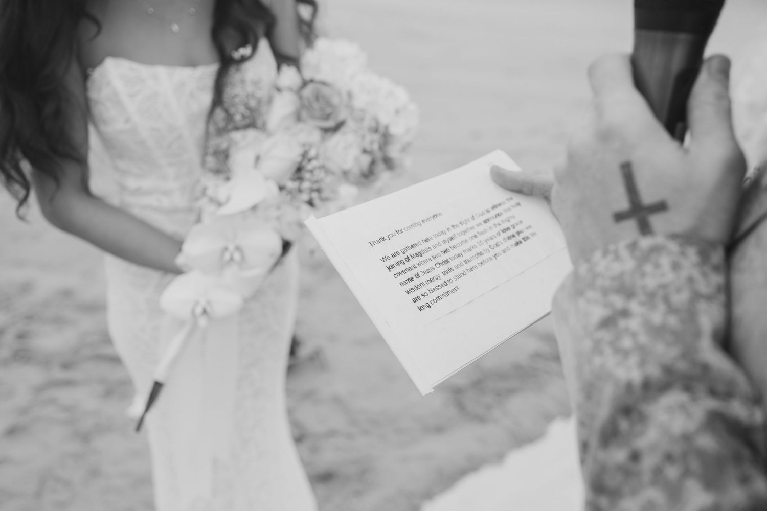 Black and white photo showing a wedding ceremony document held by someone wearing a white dress and lace gloves.