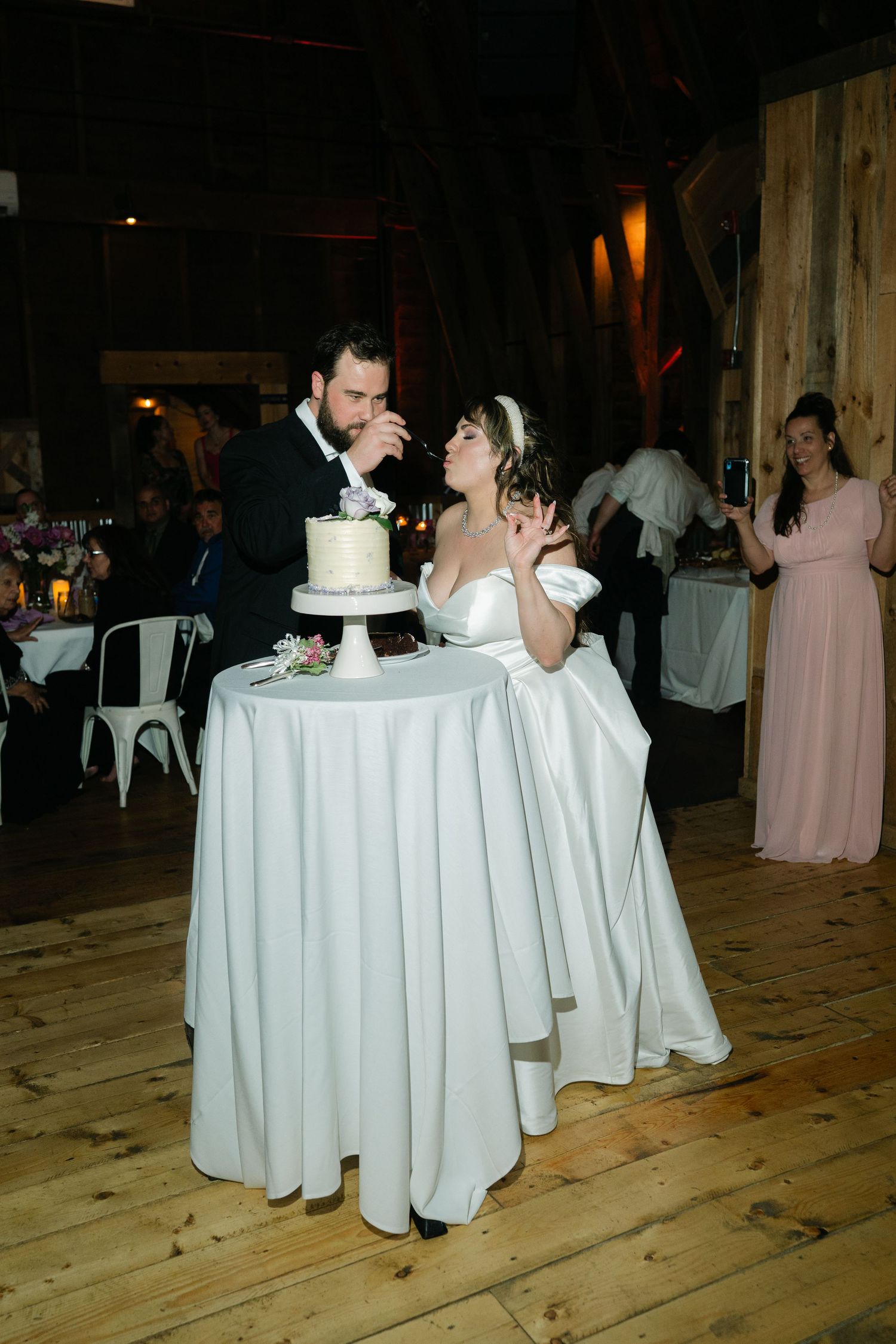 A couple shares an intimate moment at their wedding reception while seated at a round table.