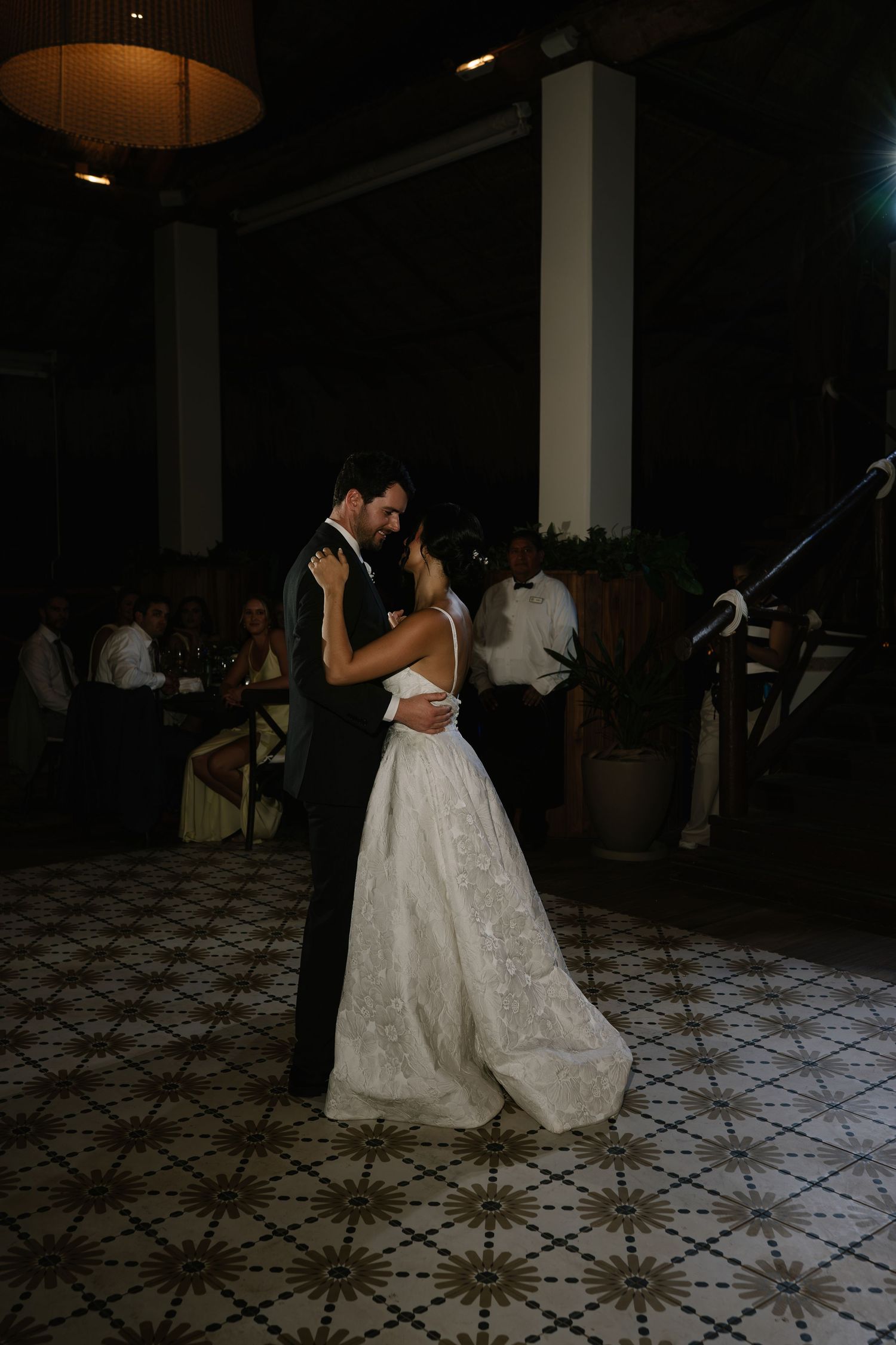 Couple in formal attire dancing together at a wedding reception on a patterned floor.