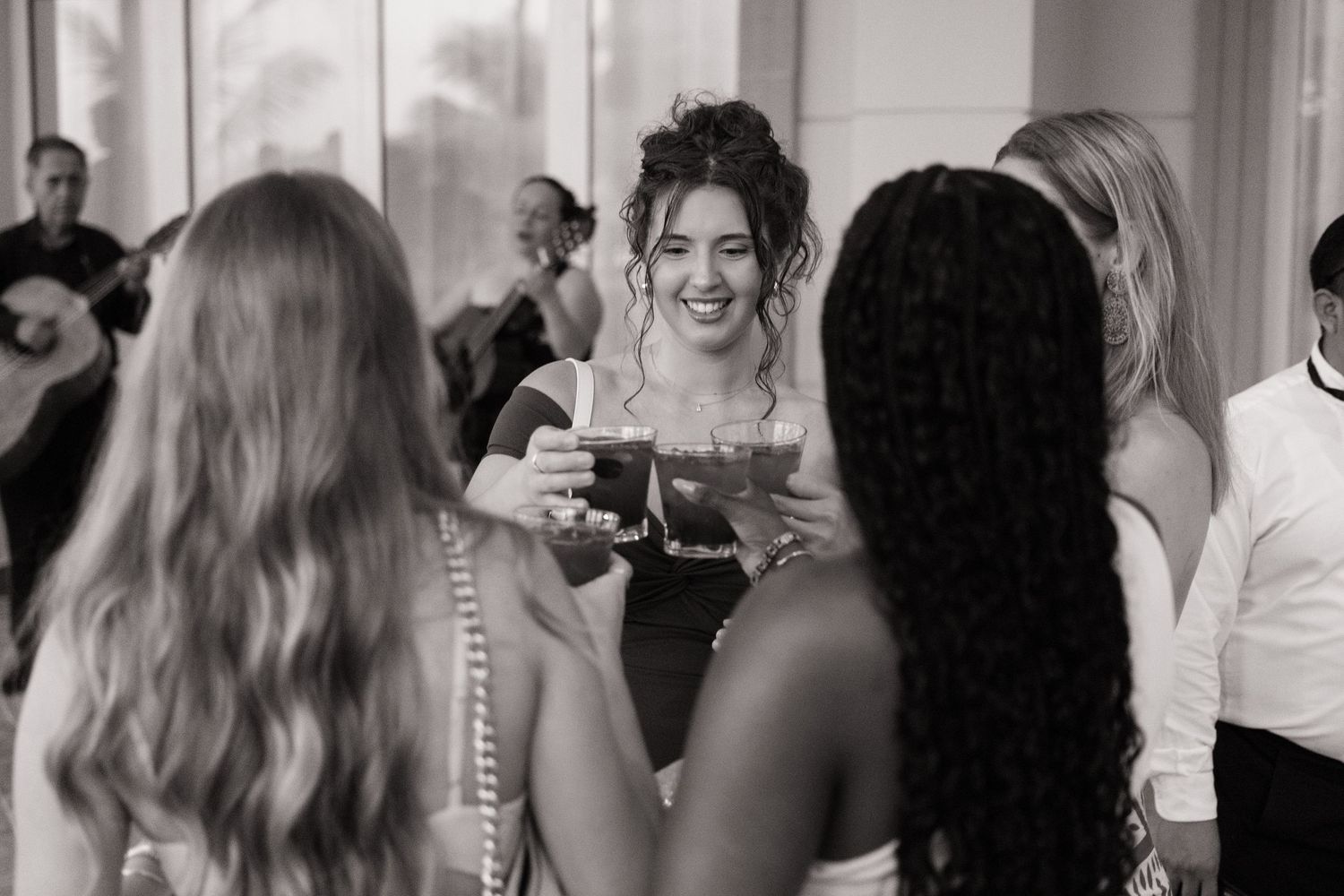 Wedding guests dance and celebrate together on a crowded dance floor at an indoor reception venue.