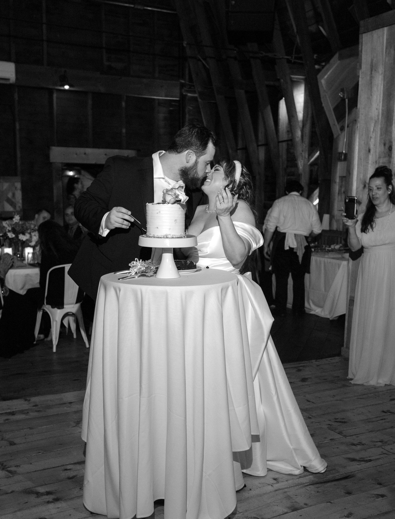 Wedding reception venue with round tables covered in white linens and dim ambient lighting.