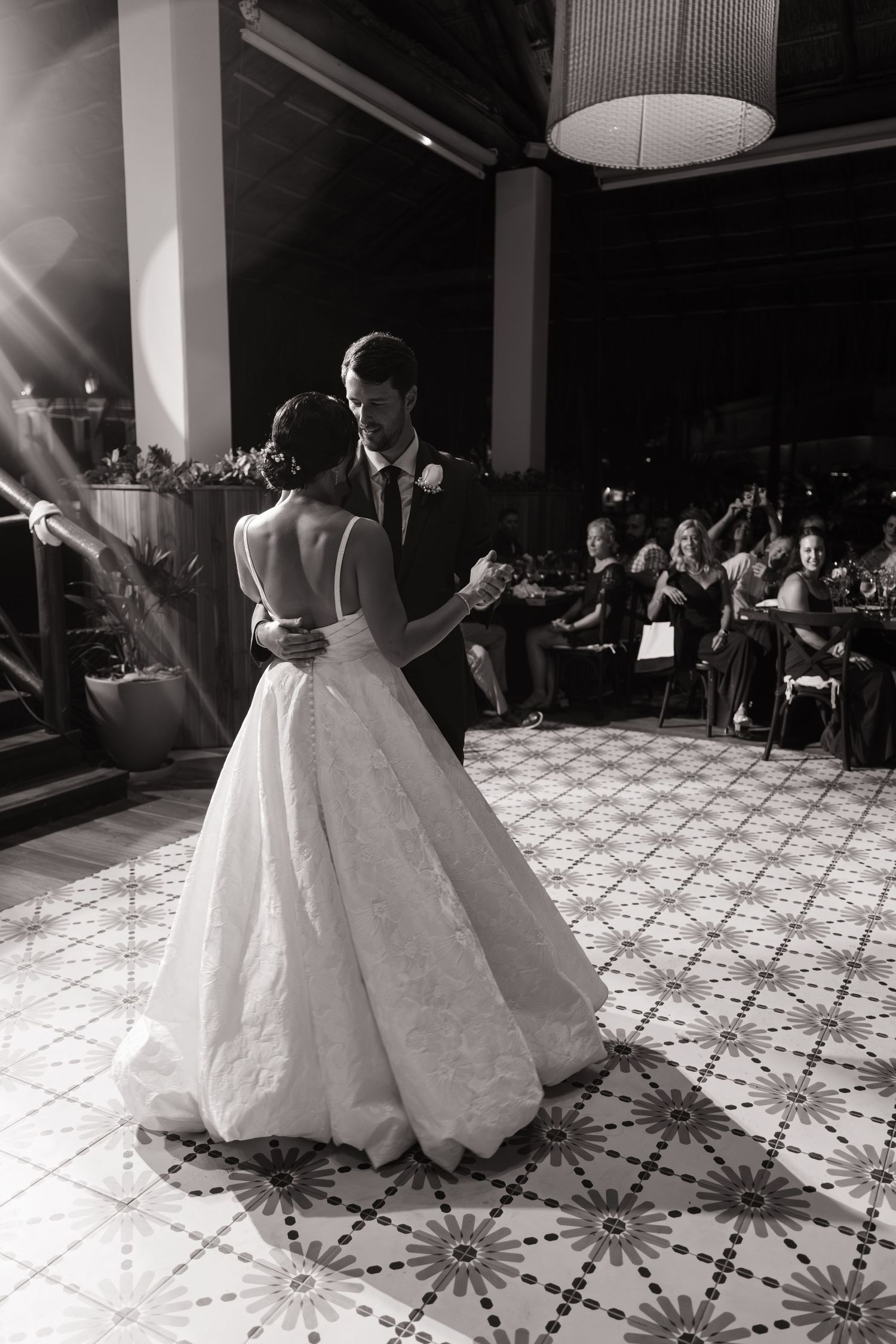 A bride in a voluminous white wedding gown twirls on a patterned dance floor during her reception.
