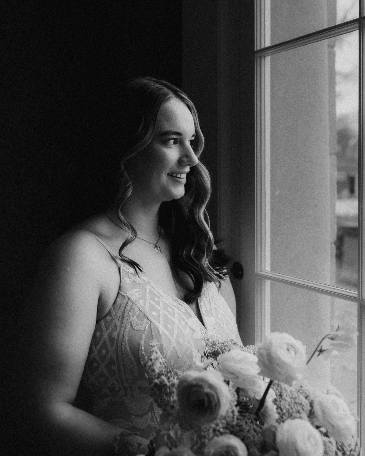 Artistic black and white bridal portrait by window with natural light.