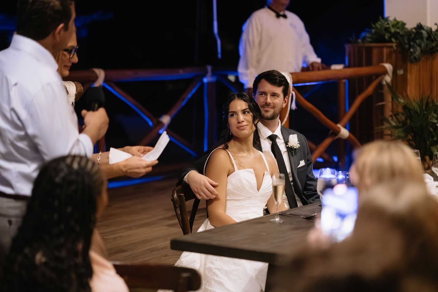 Wedding reception guests dance together on a dimly lit dance floor during evening celebrations.