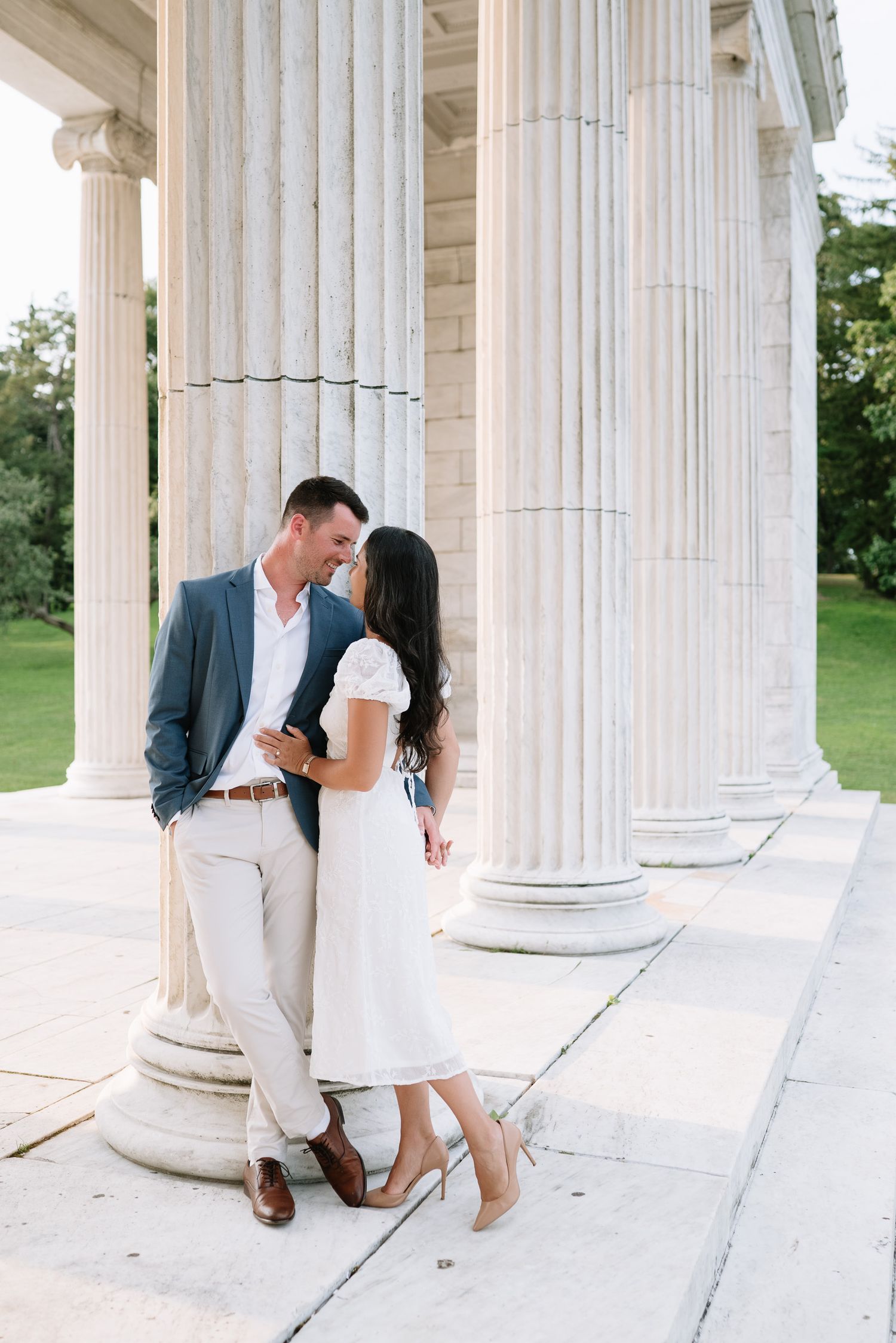 Romantic photo sequence of couple playing between classical white pillars outdoors.