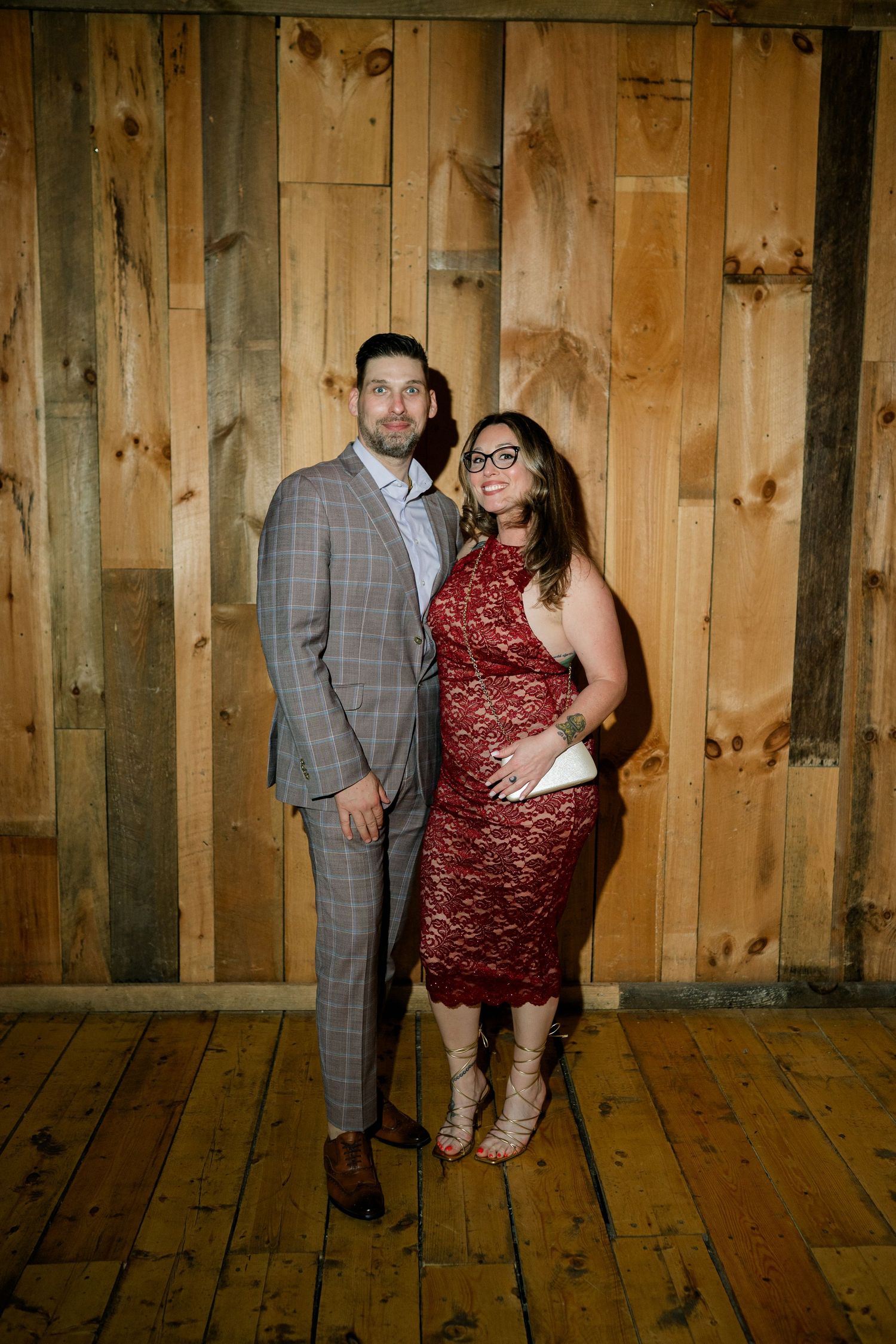 A rustic barn venue with wooden walls and floors serves as backdrop for formal event photos.