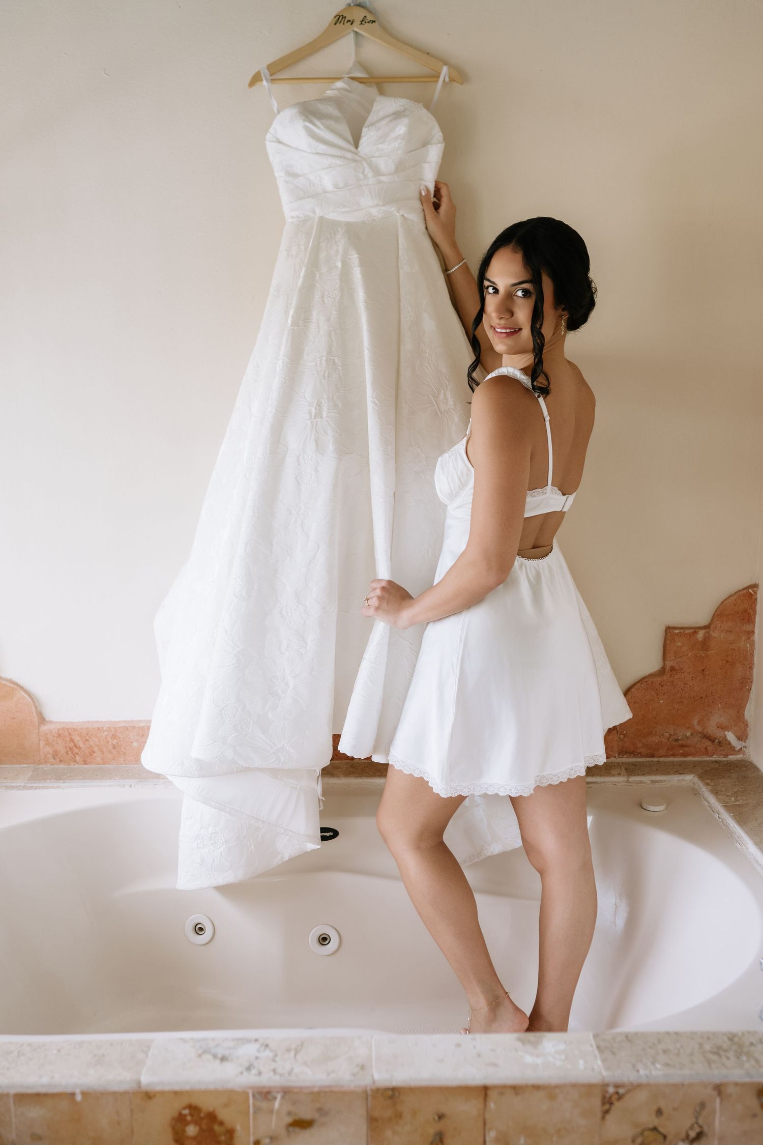 A series of artistic boudoir photos showing a white wedding dress hanging while someone poses playfully behind it.