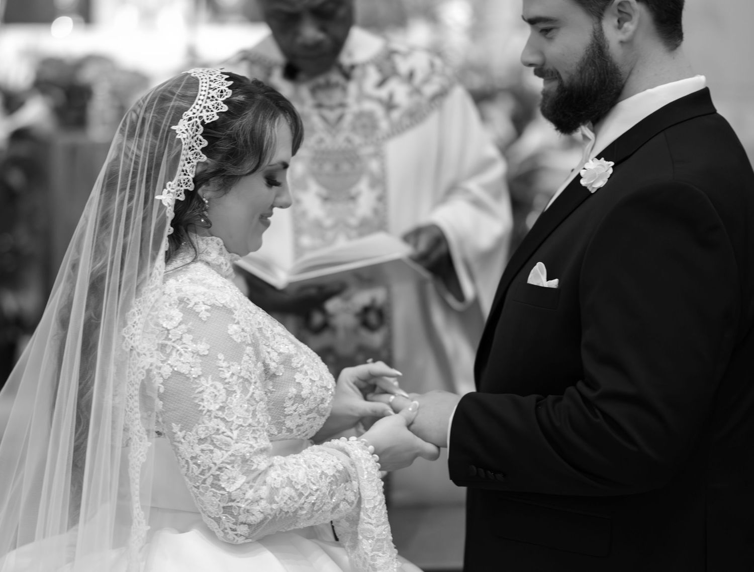 A couple shares an intimate moment during their wedding ceremony, with the bride wearing a lace veil and white dress.