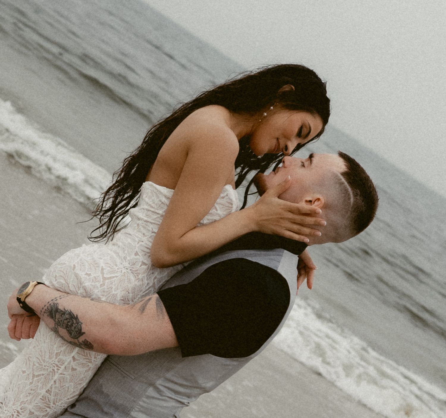 A romantic couple embraces on a misty beach, with waves rolling in the background.