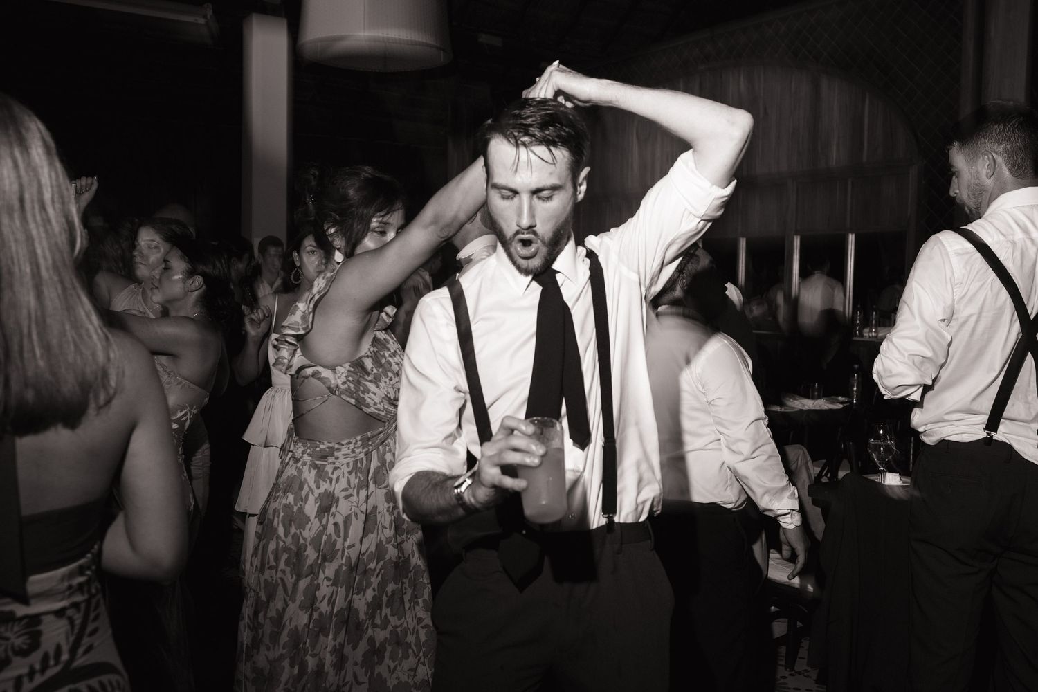 Wedding reception guests dancing and celebrating on a crowded dance floor.