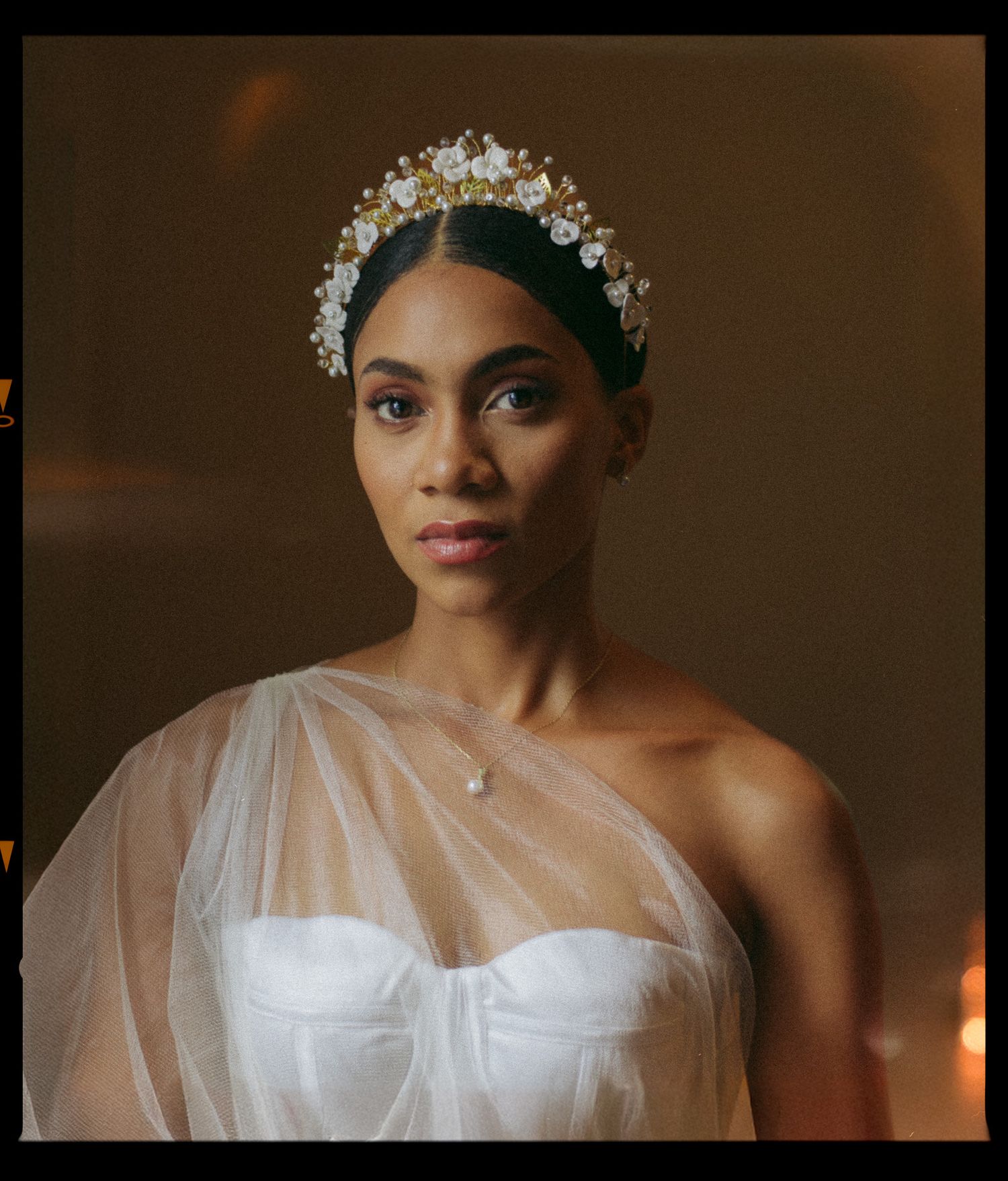 Bride wearing crystal headpiece and sheer one-shoulder wedding gown.