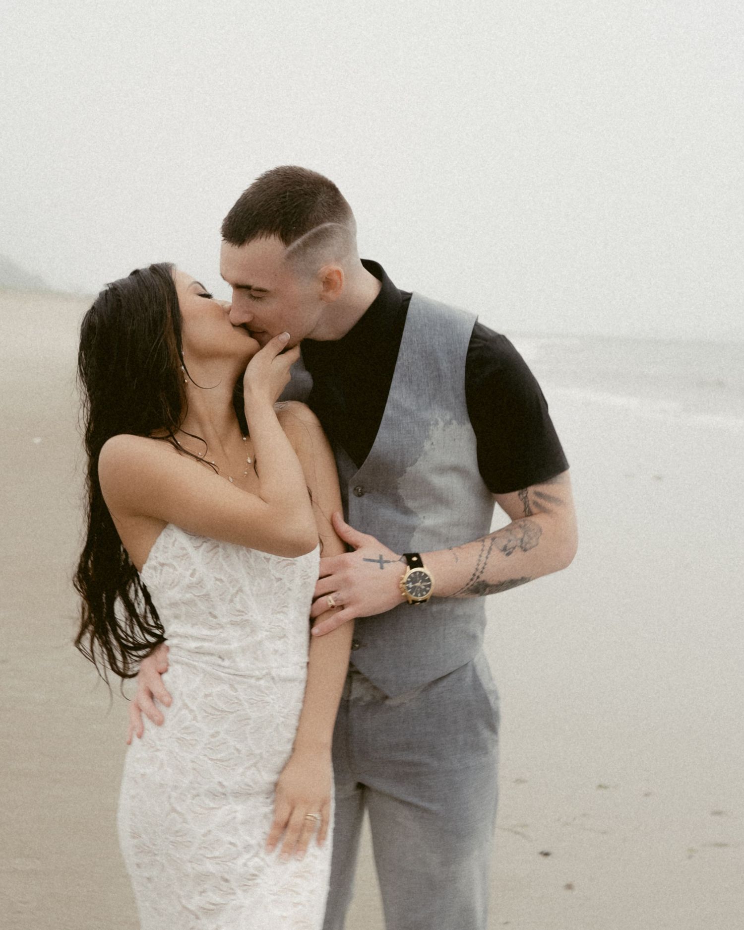 A romantic beach engagement moment with a couple in casual and formal attire.