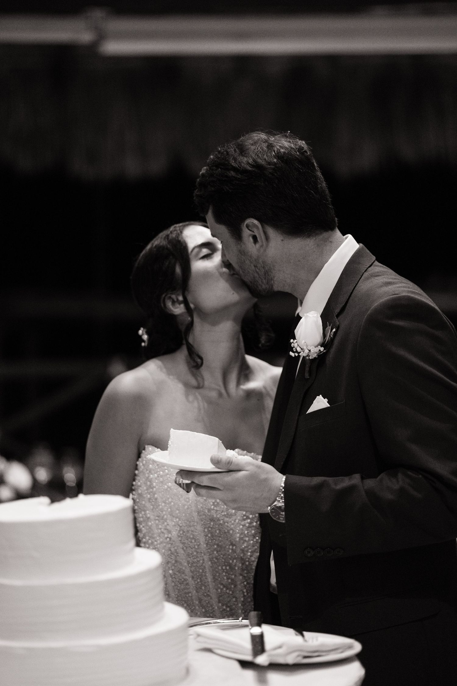 A romantic black and white wedding photo series showing a couple sharing intimate moments while cutting their wedding cake.