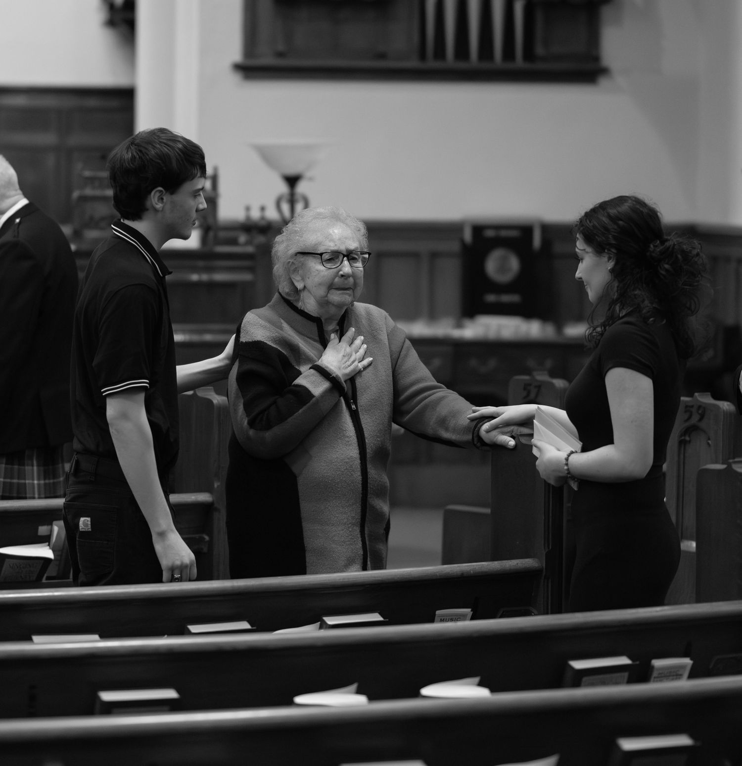 Black and white photo showing people interacting at a business counter or service desk.