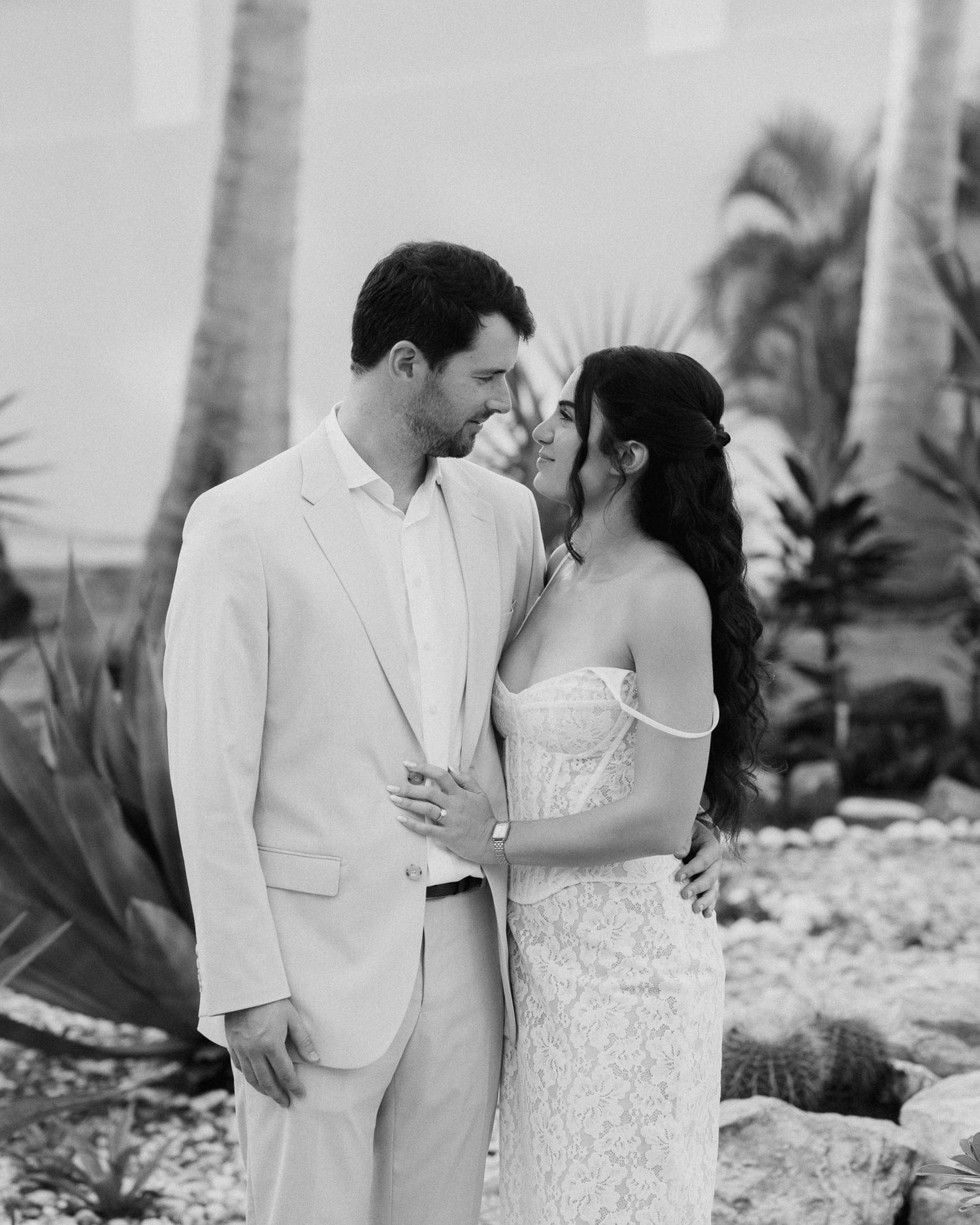Romantic beach wedding portraits in white attire with tropical scenery.