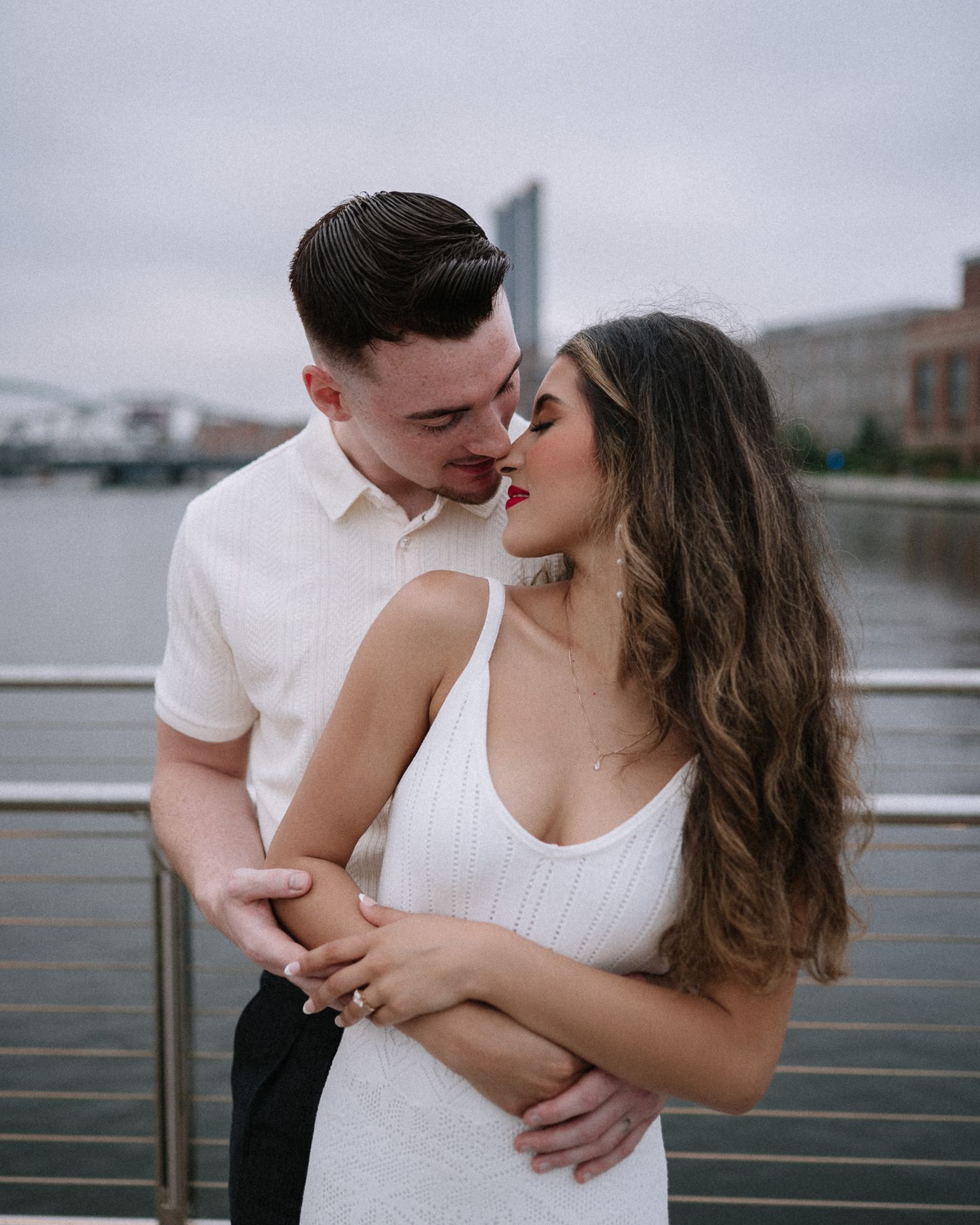 Tender moment between couple during waterfront photoshoot.
