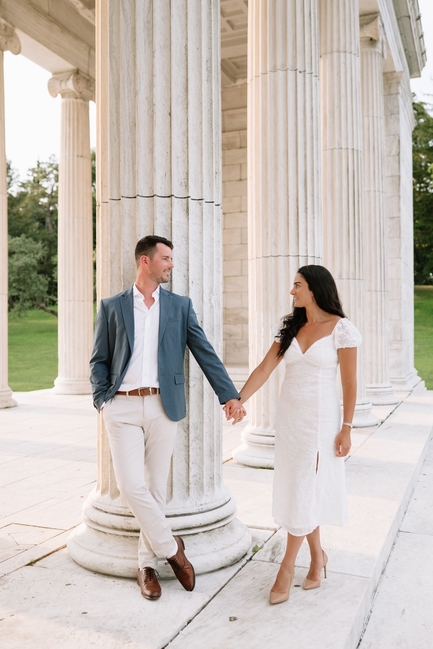Candid moments captured between couple during architectural photo session with white columns.