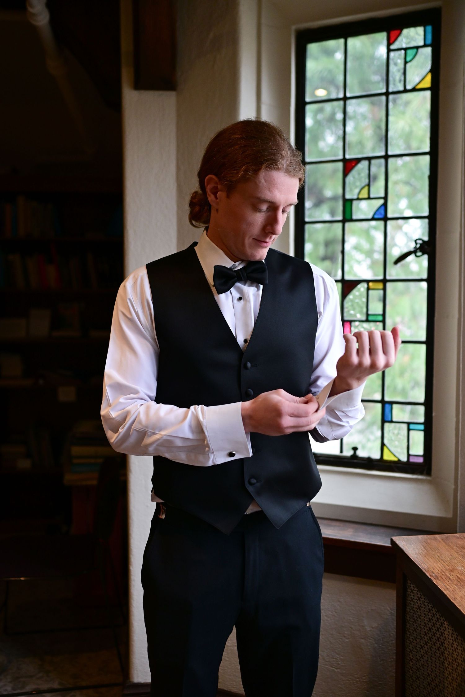 Person in formal attire checks phone by window in series of candid shots showing natural lighting.