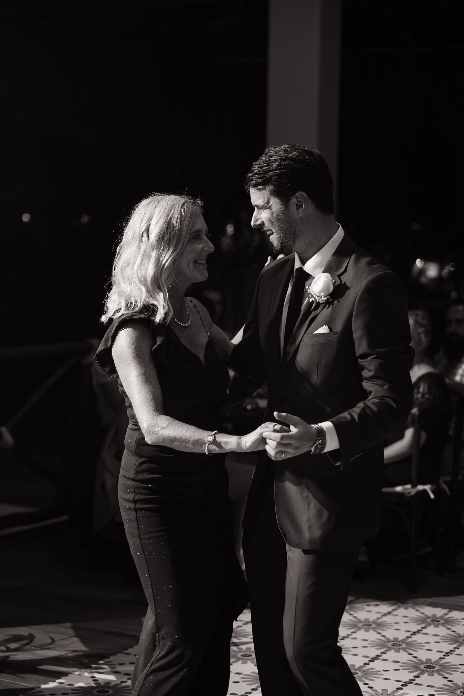 Couple dancing intimately in black and white on a dimly lit dance floor.