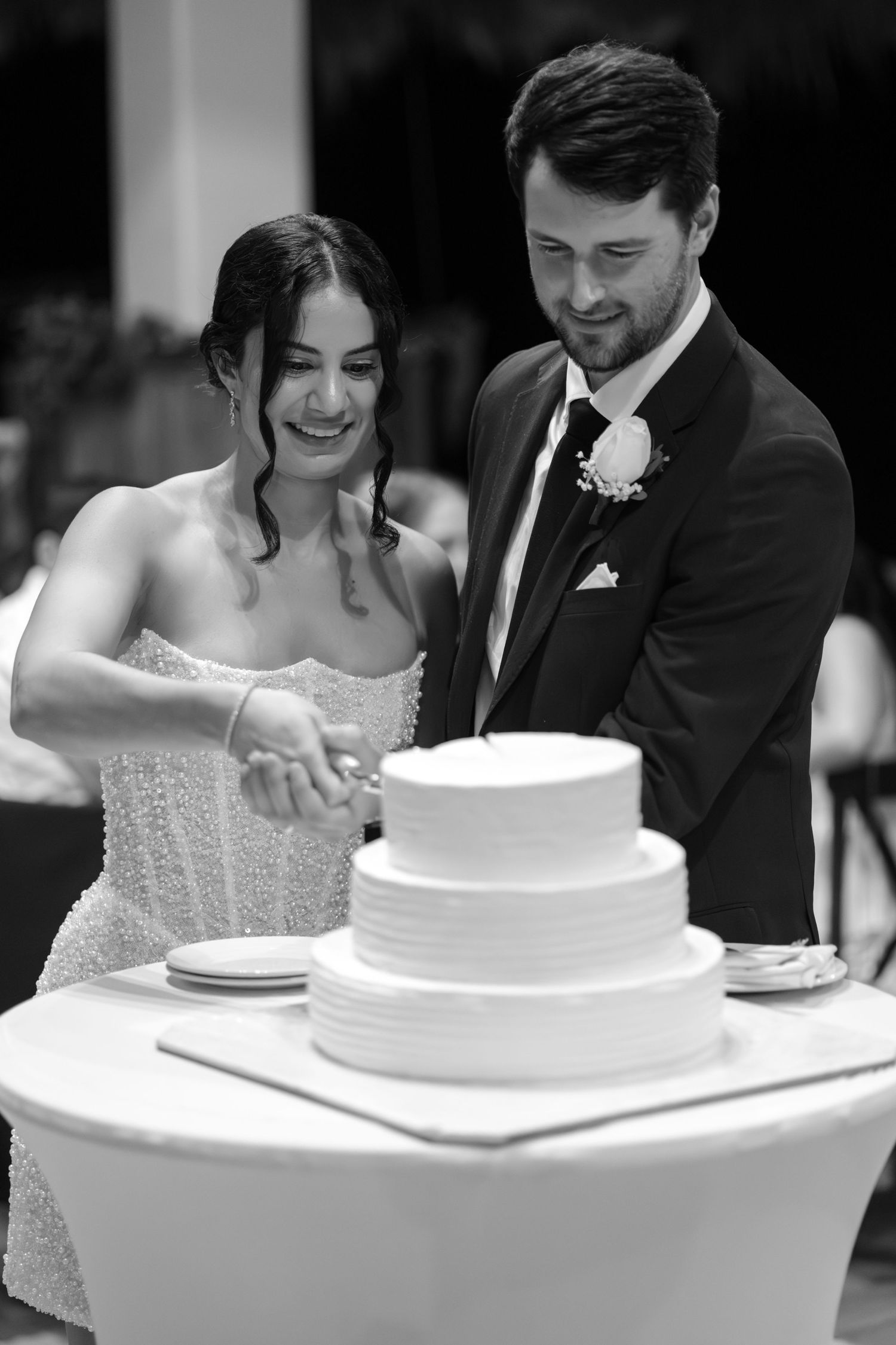 Newlyweds cutting their traditional white tiered wedding cake together.