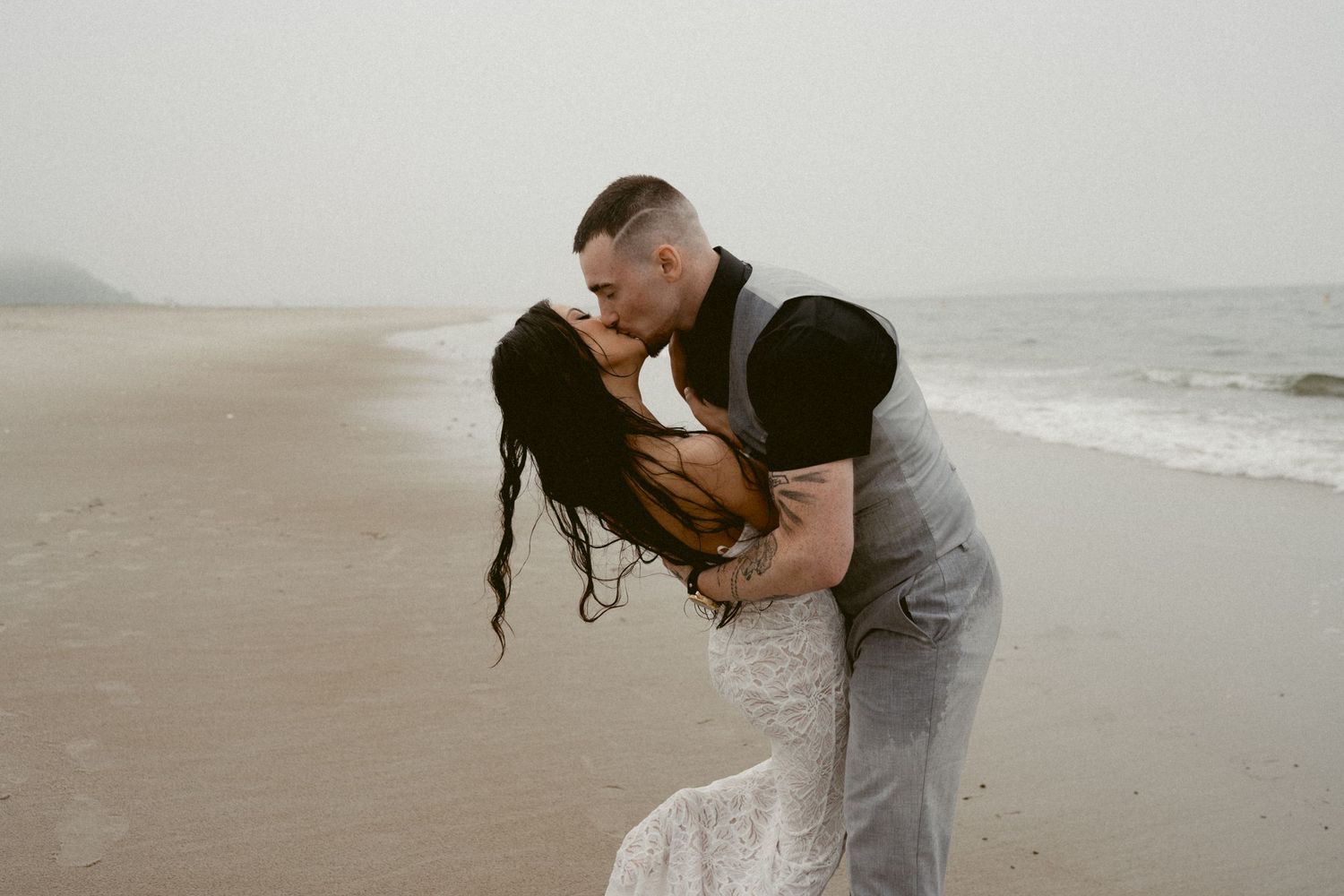 A romantic beach photoshoot featuring a couple in wedding attire by the ocean waves.