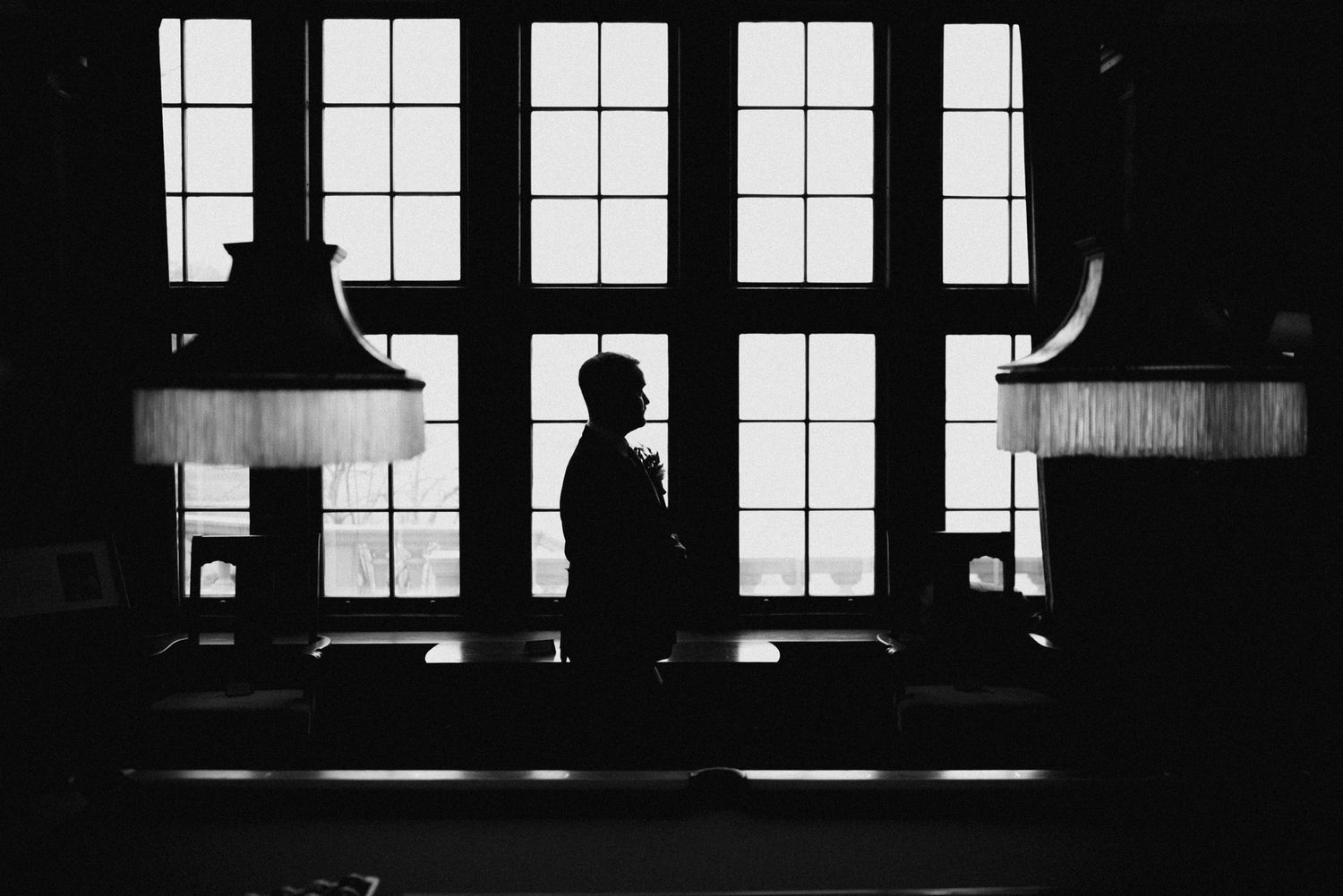 A dramatic silhouette against large windows in an elegant interior space.