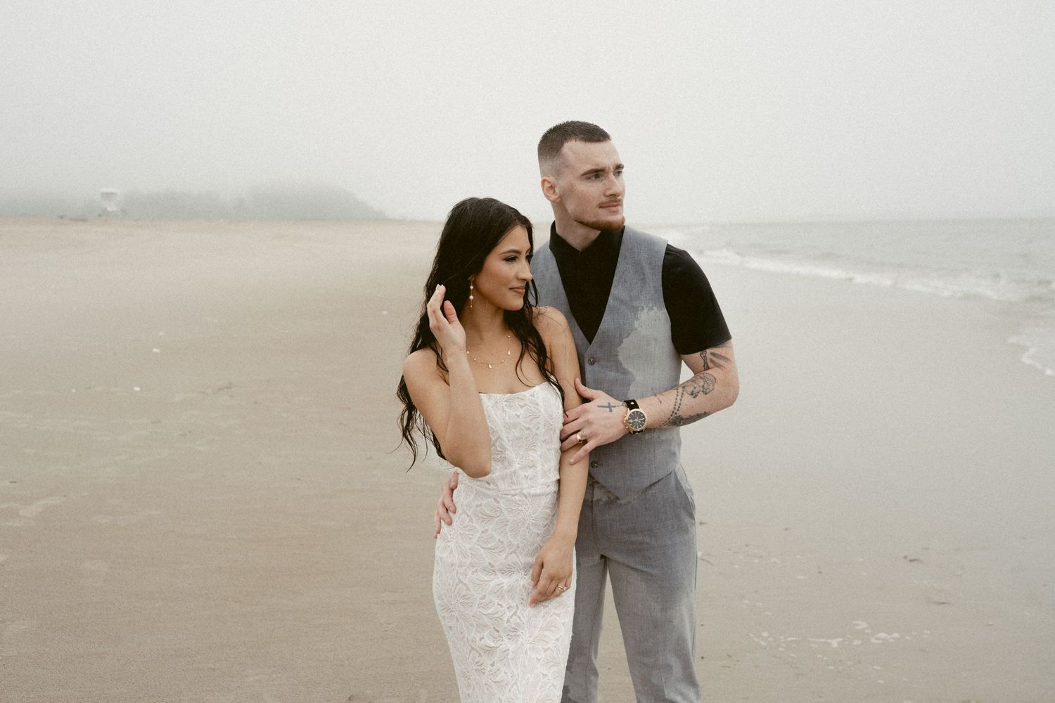 A couple shares a romantic moment together on a misty beach during their wedding photoshoot.