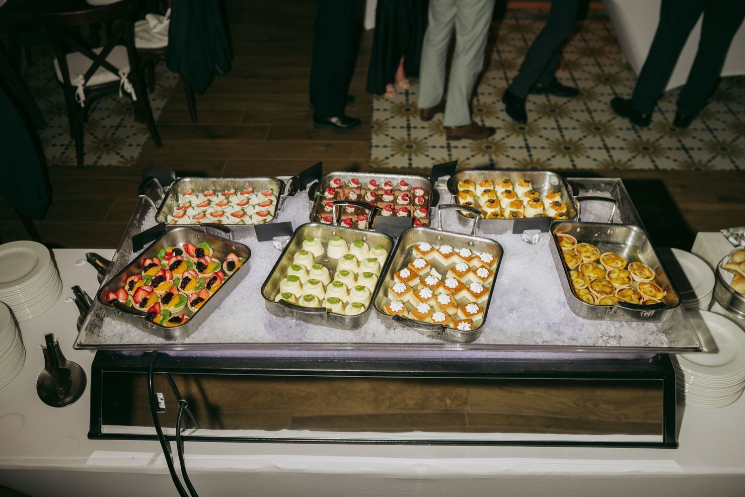 Elegant catering display features rows of appetizers and hors d'oeuvres arranged on silver platters at an upscale event.