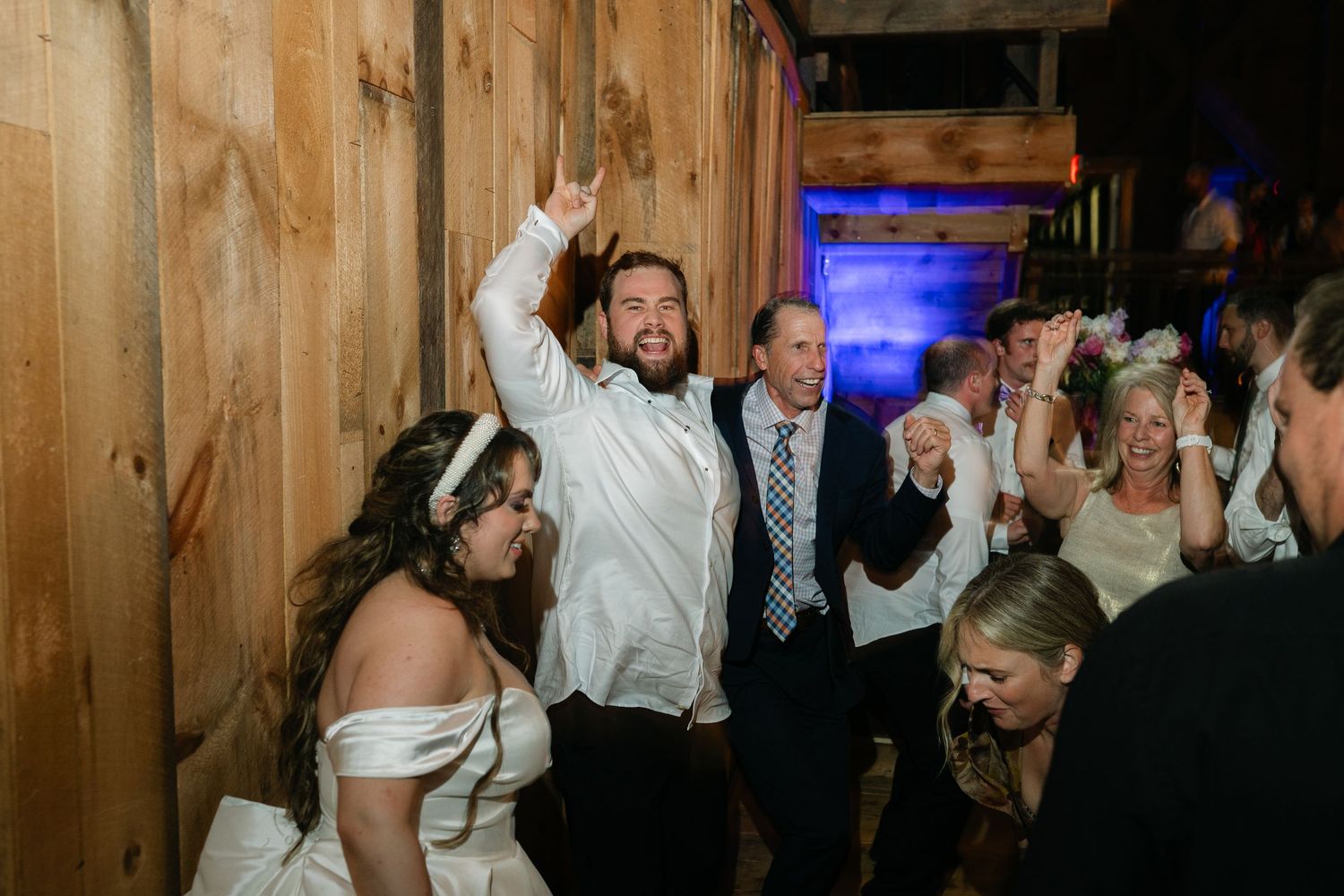 Wedding reception celebration in a rustic wooden venue with party guests dancing and celebrating.