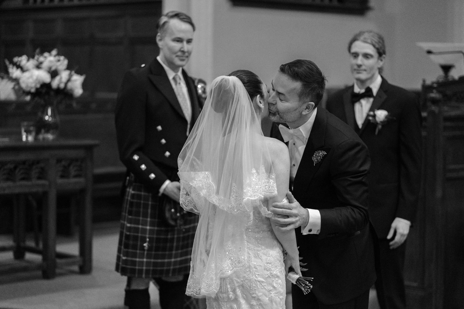 Wedding ceremony taking place in traditional church sanctuary with stained glass windows.