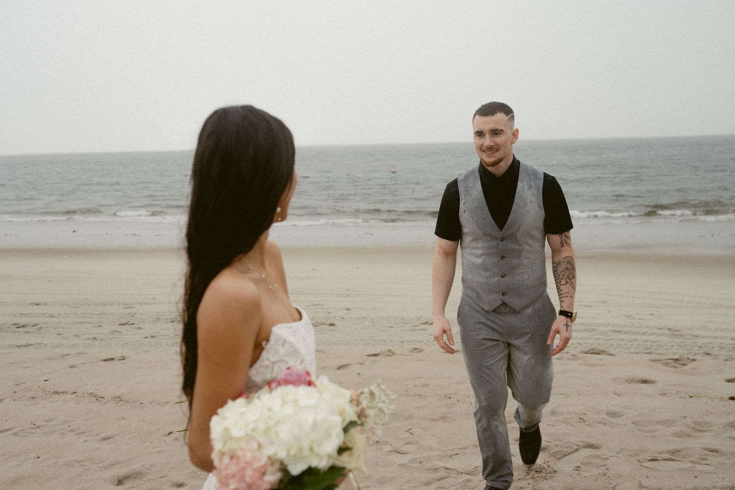 A couple shares a romantic moment on a misty beach as they pose for wedding photos.