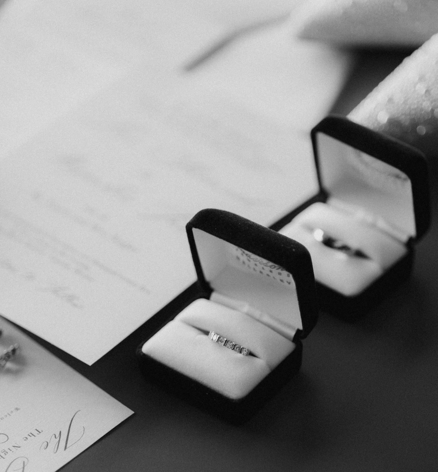 Two elegant wedding rings displayed in black jewelry boxes on a light surface.
