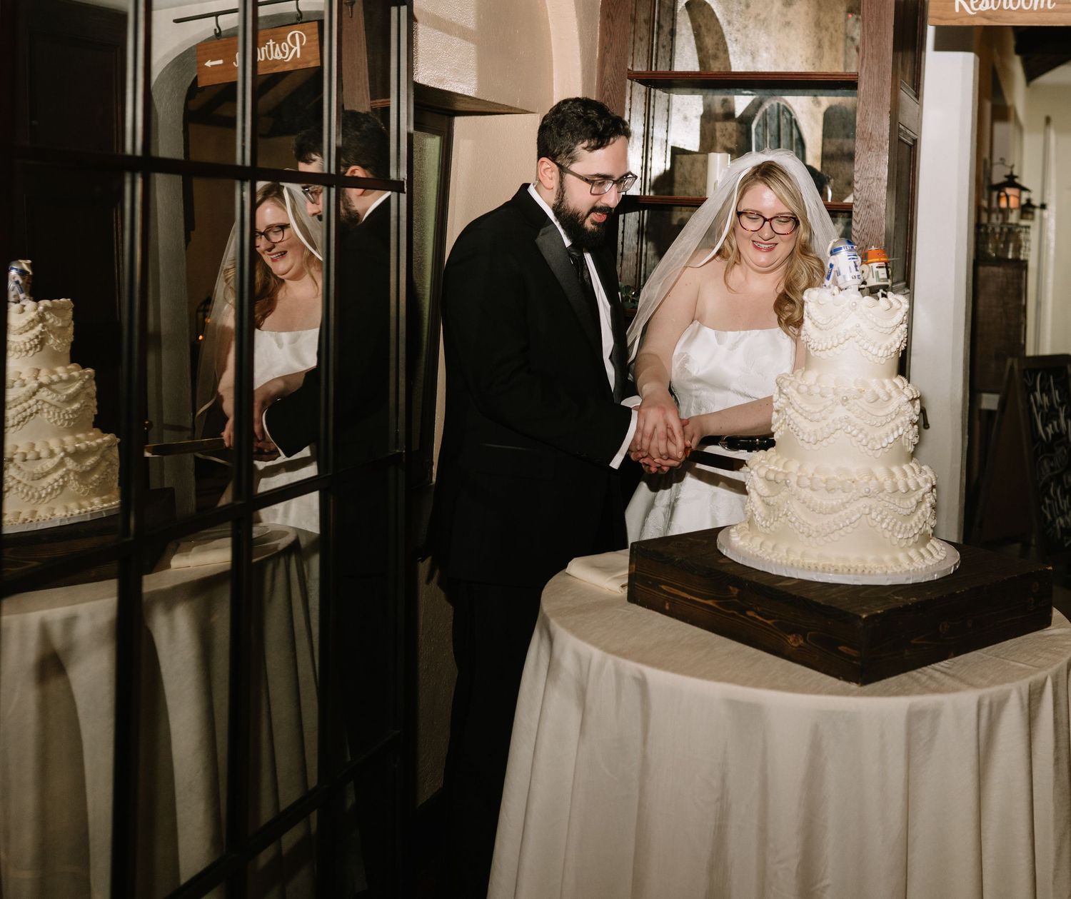 A couple cutting their wedding cake at an elegant indoor reception venue.