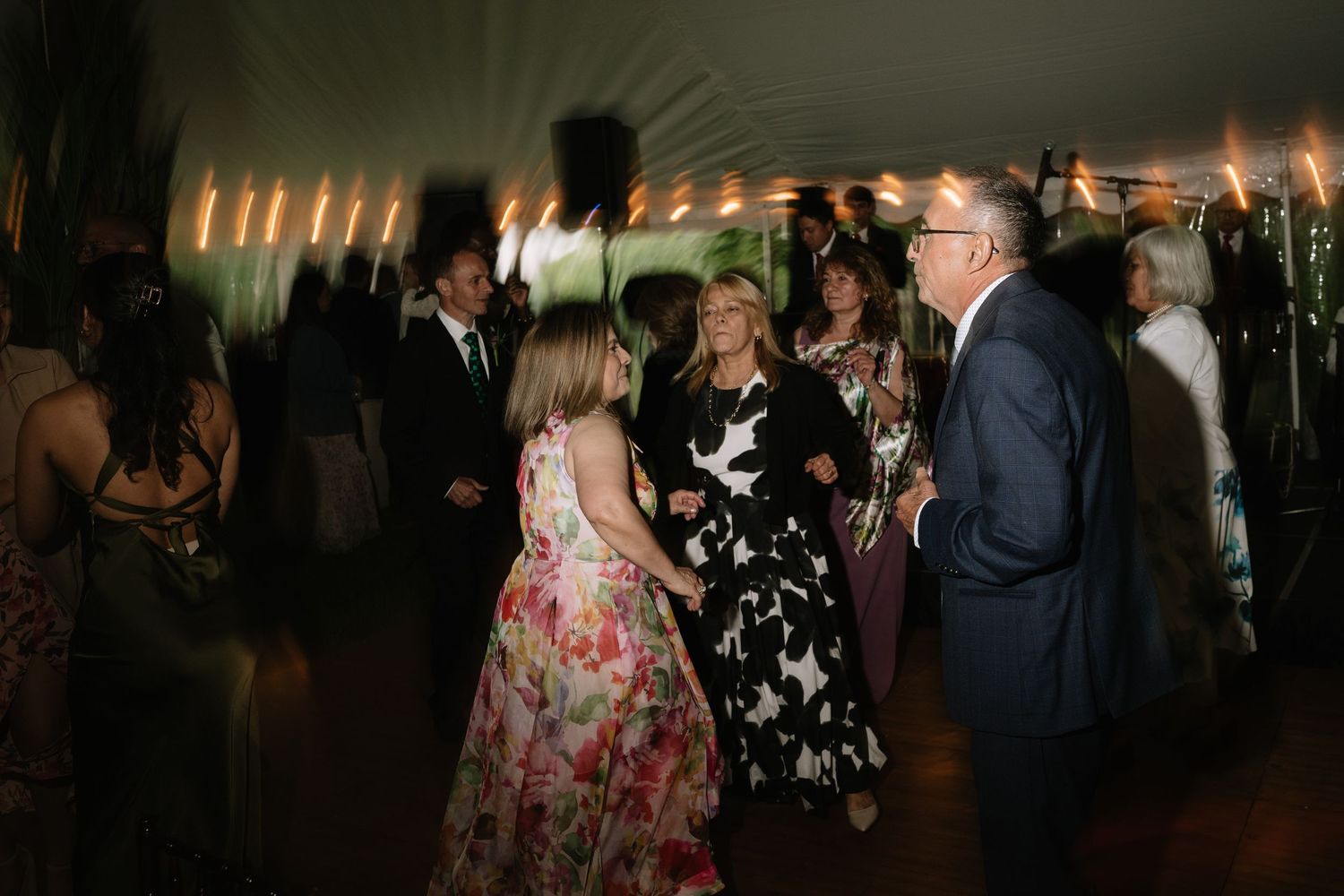 Elegantly dressed guests dancing together under candlelight at a festive wedding reception.