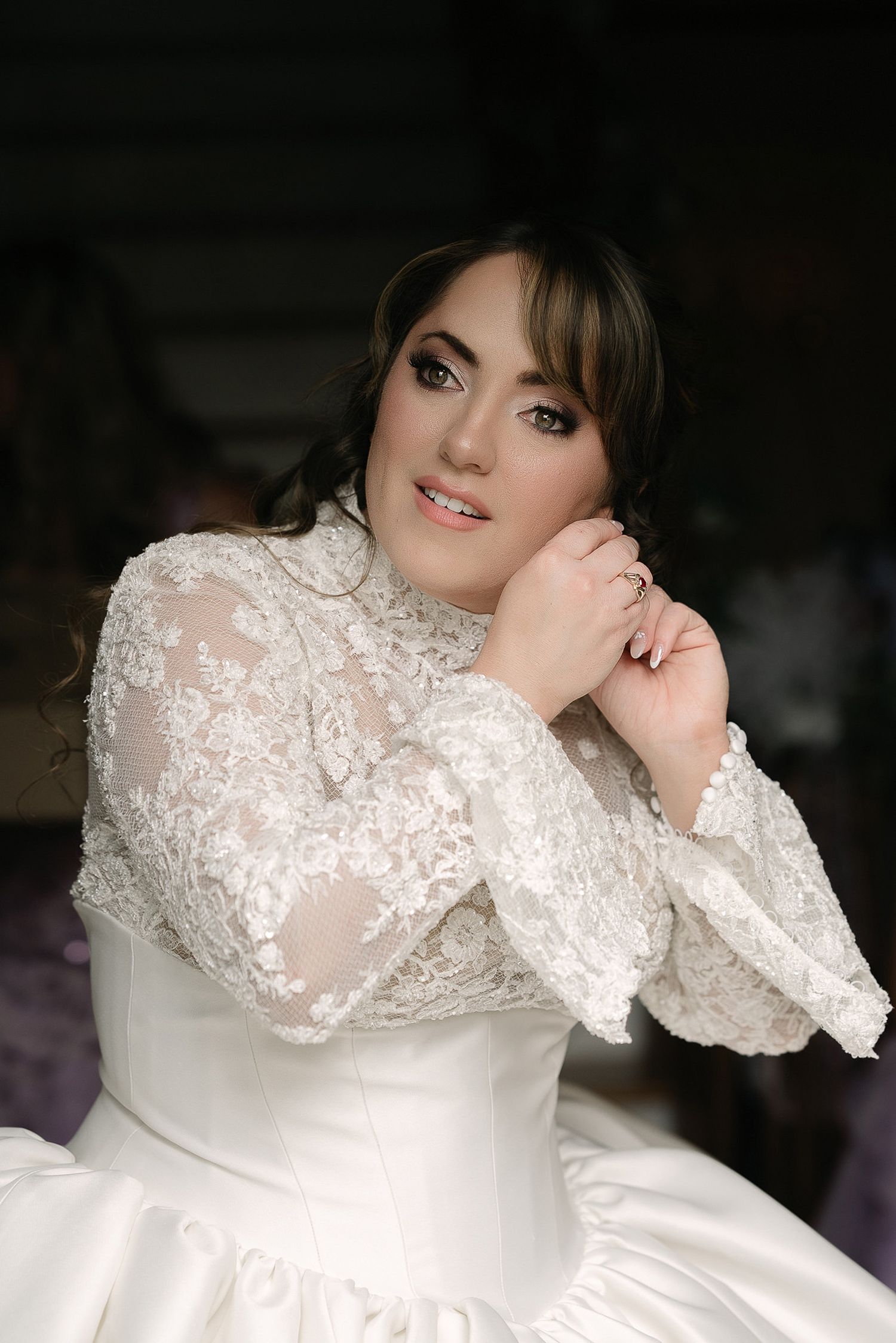 Elegant bridal portrait featuring a white lace gown with long sleeves.