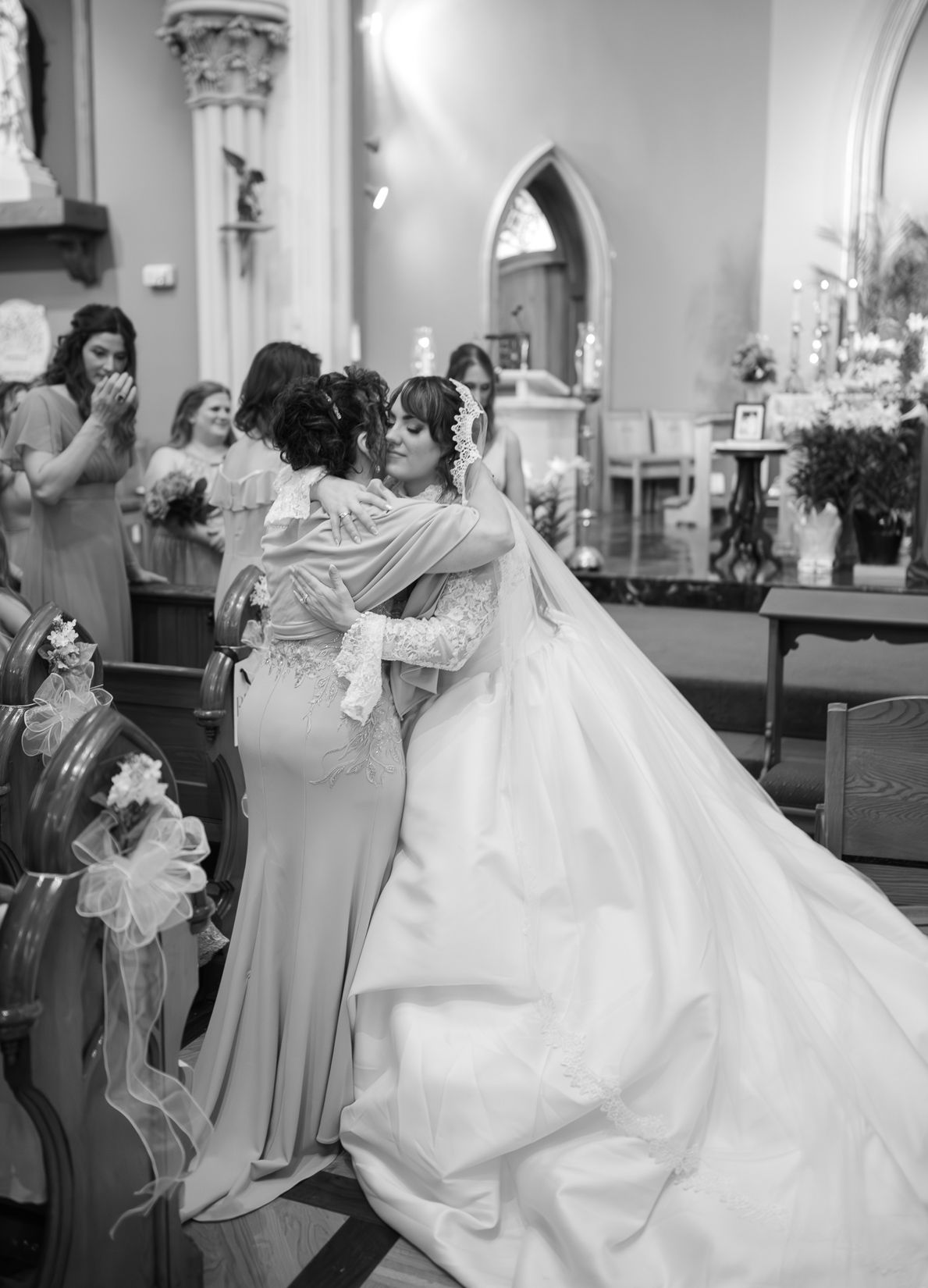 Black and white wedding photo capturing an emotional embrace in a church setting.