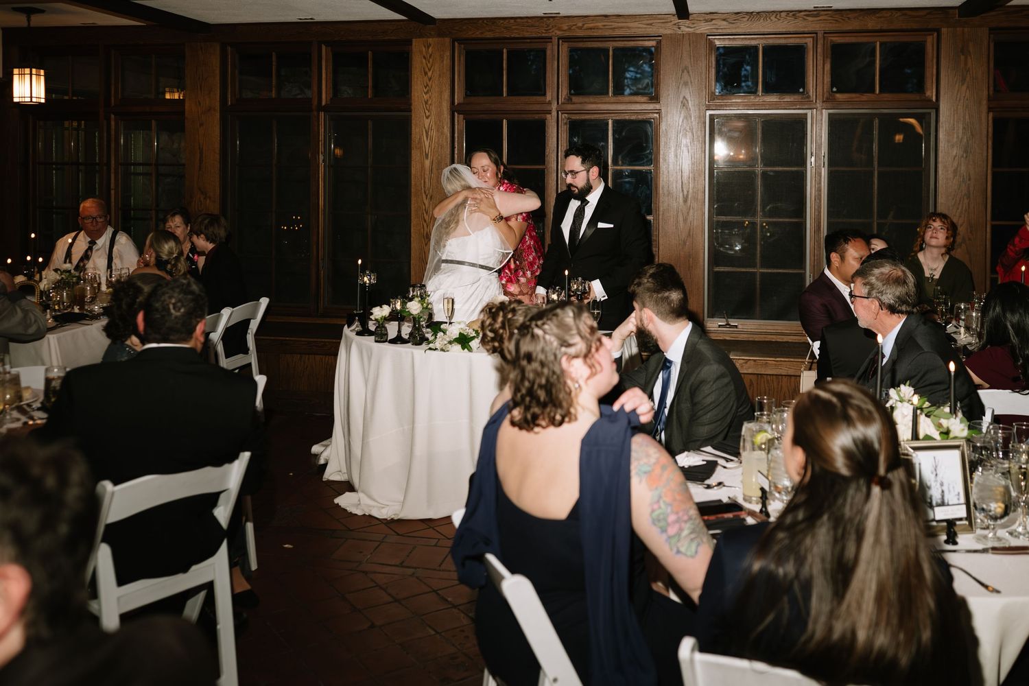 Bride and groom share a kiss at their sweetheart table during wedding reception dinner.