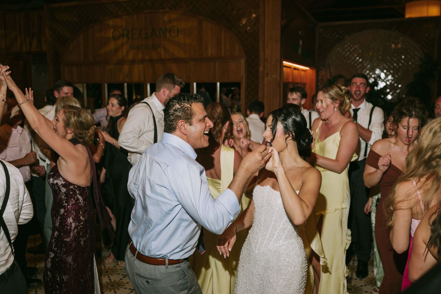 Wedding party members dance in a line during a festive reception celebration.