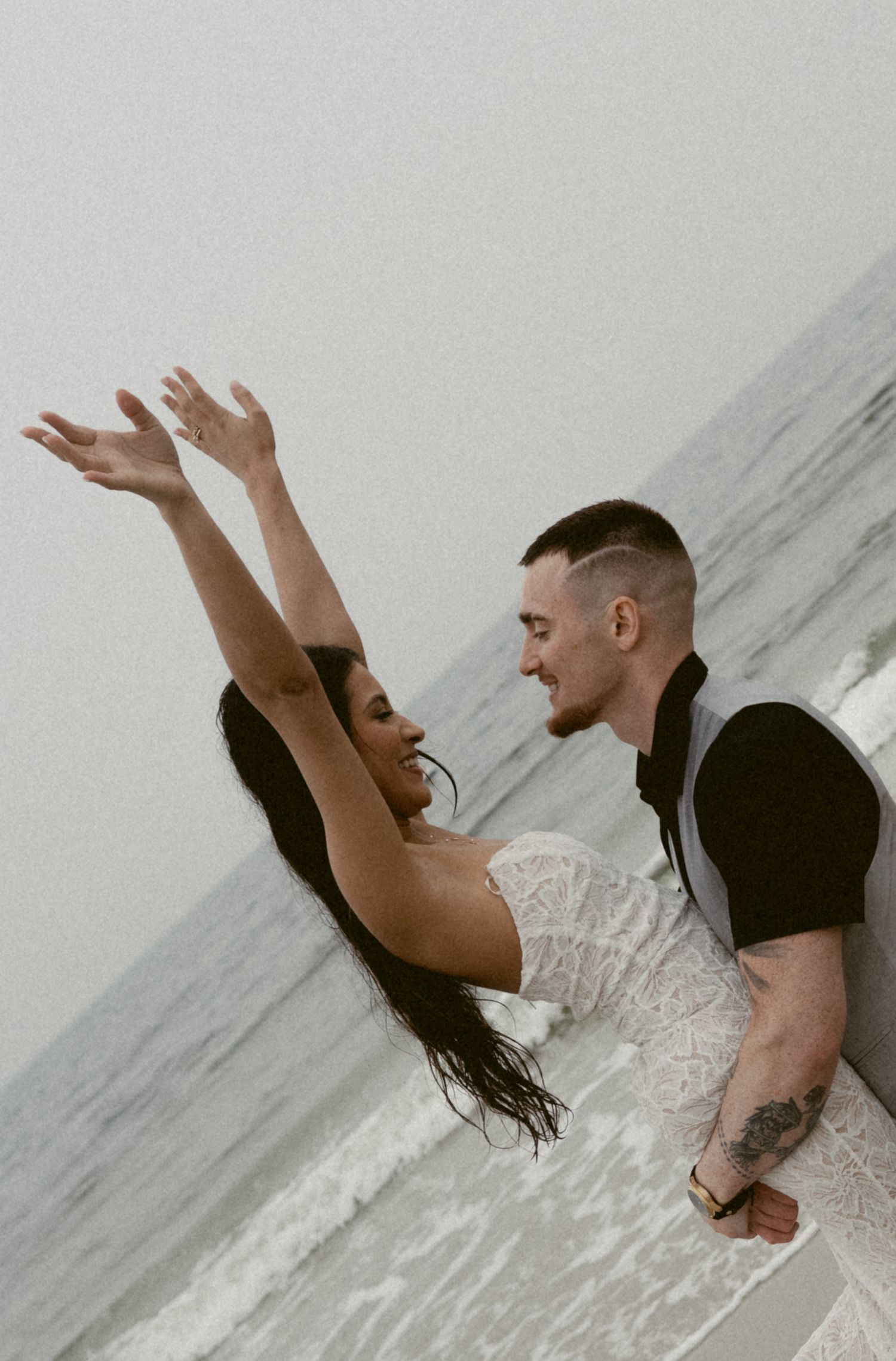 A joyful couple dances together on the beach during their wedding celebration.