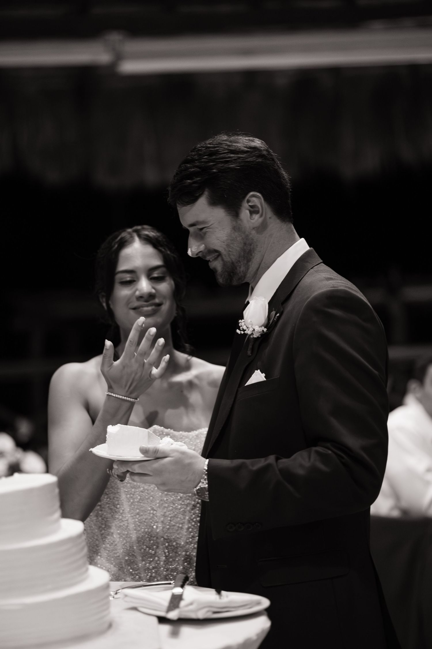 Couple shares an intimate moment while cutting their white wedding cake at the reception.
