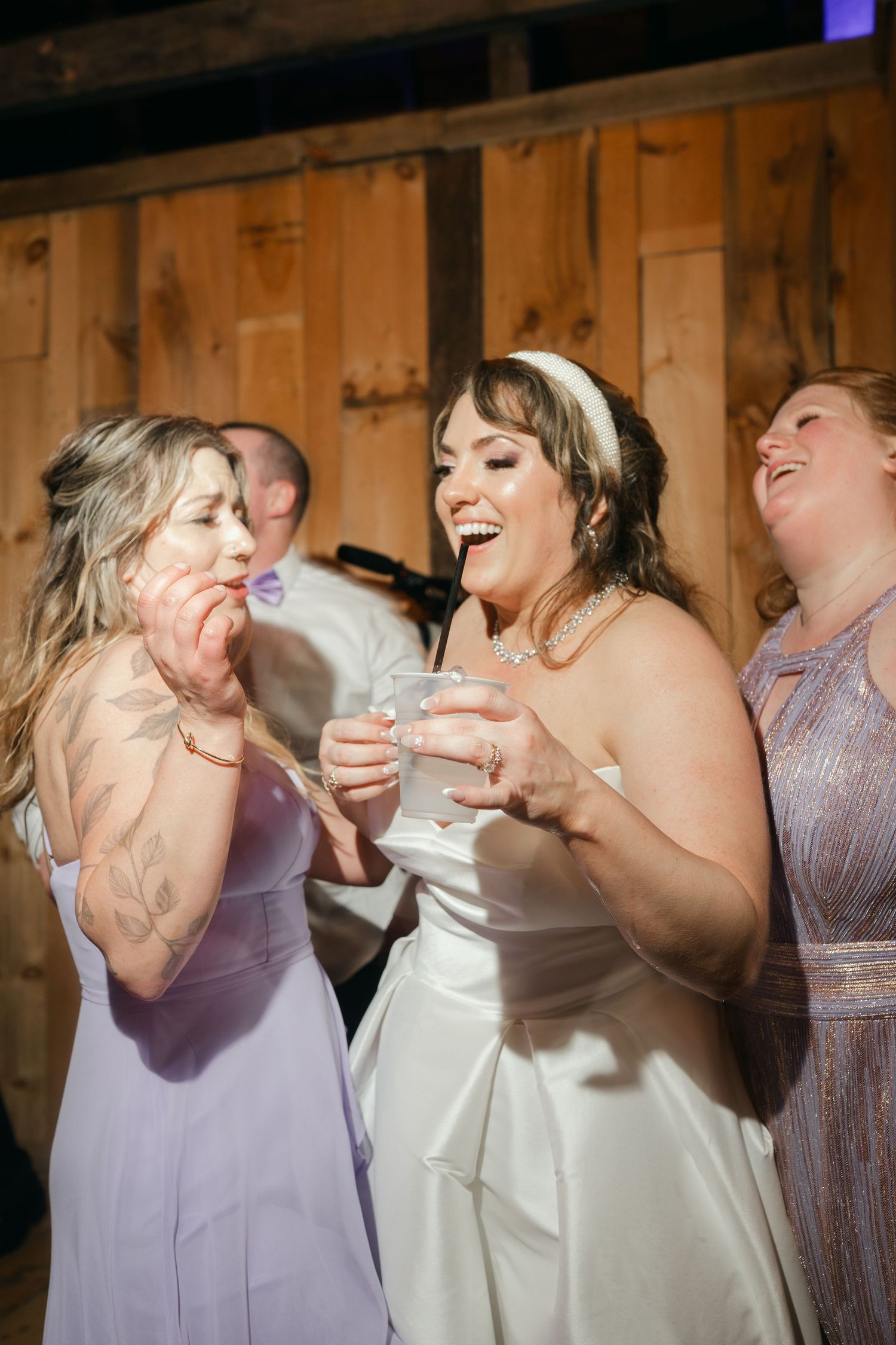 Wedding celebration captures joyful laughter during reception in rustic barn setting.