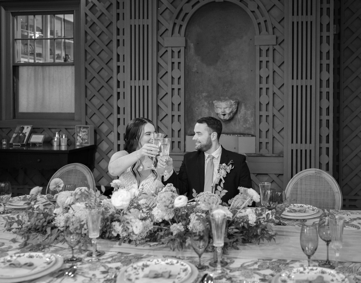 Vintage black and white photo of a couple at an elegant wedding reception table with ornate decorations.